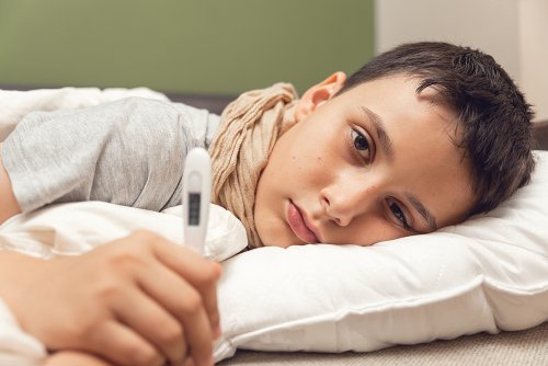 Un garçon malade avec un thermomètre allongé dans son lit. Enfant malade avec fièvre et maladie au lit. | Photo : Shutterstock