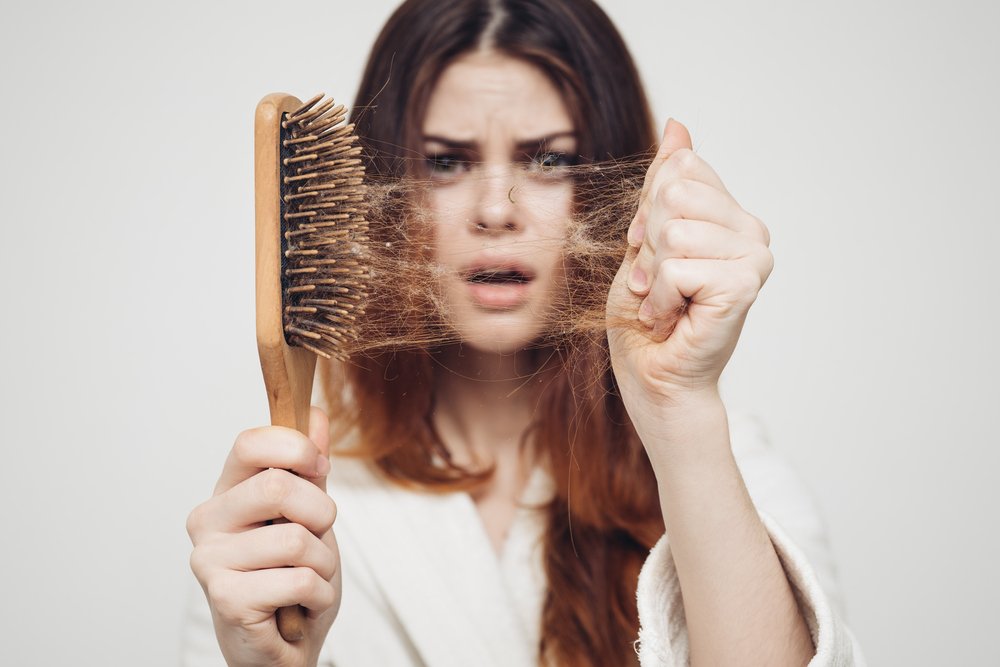 Chica con un peine y un problema de pérdida de cabello. Fuente: Shutterstock