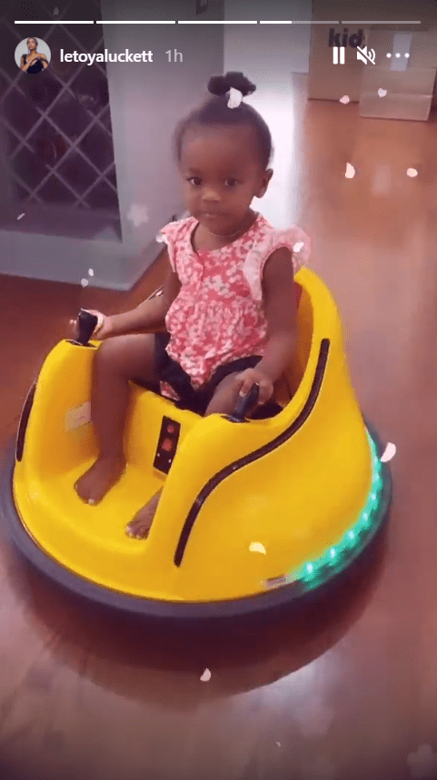 LeToya Luckett's daughter, Gianna, dressed in a cute pink dress while riding a yellow bumper car | Photo: Instagram/letoyaluckett