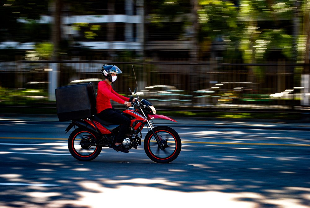 Joven trasladándose en una motocicleta para hacer la entrega de un pedido. | Foto: Shutterstock