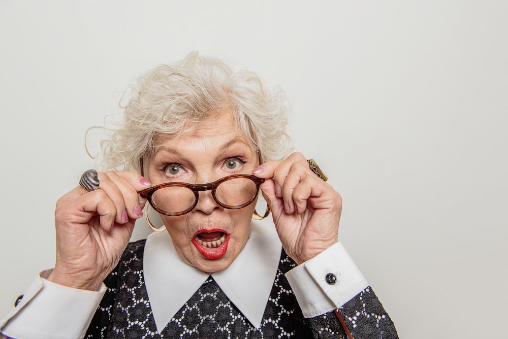 Anciana sorprendida sosteniendo sus gafas. | Foto: Shutterstock