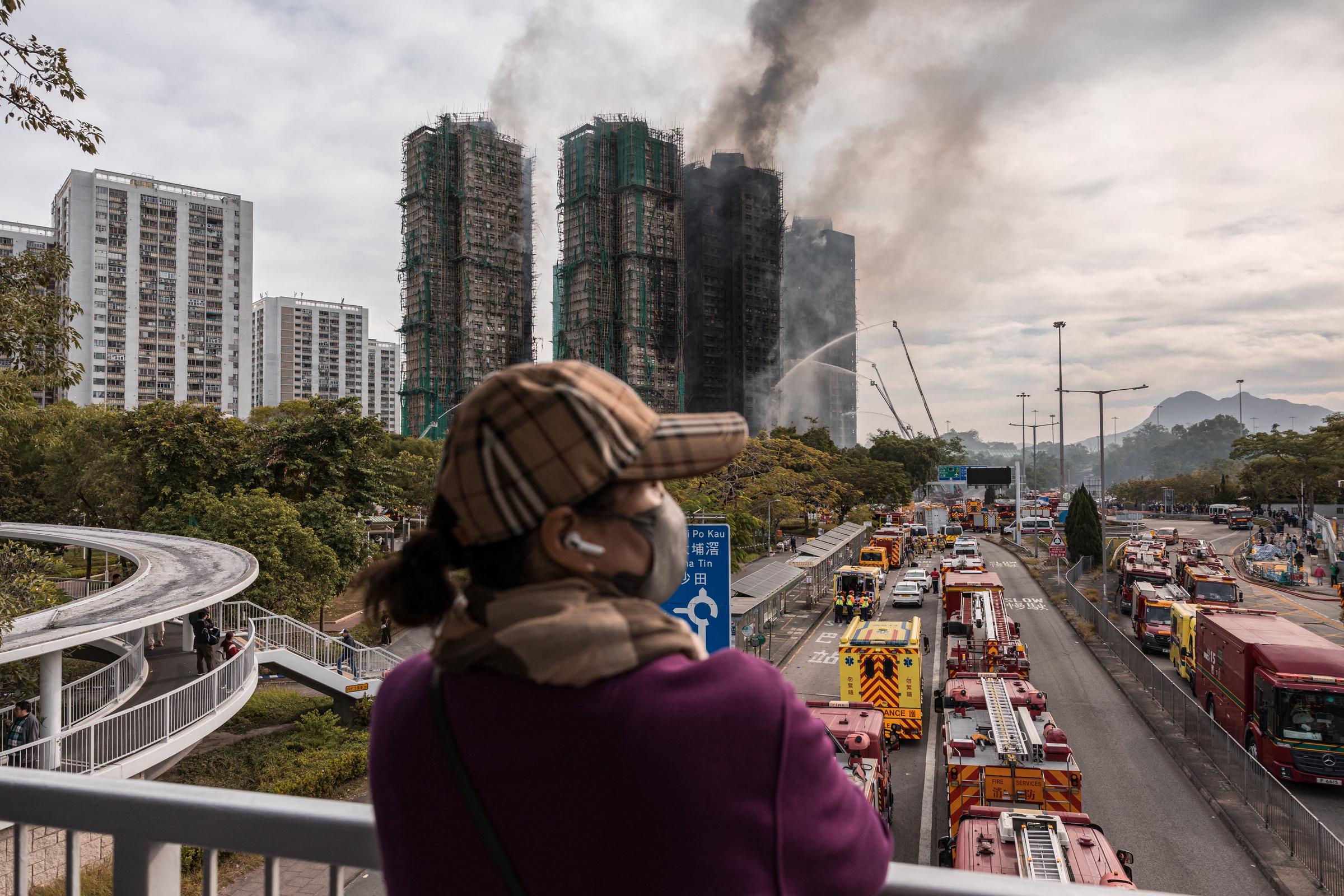 A woman watches as smoke rises from the scorched towers of Wang Fuk Court in Tai Po, Hong Kong, on November 27, 2025 | Source: Getty Images