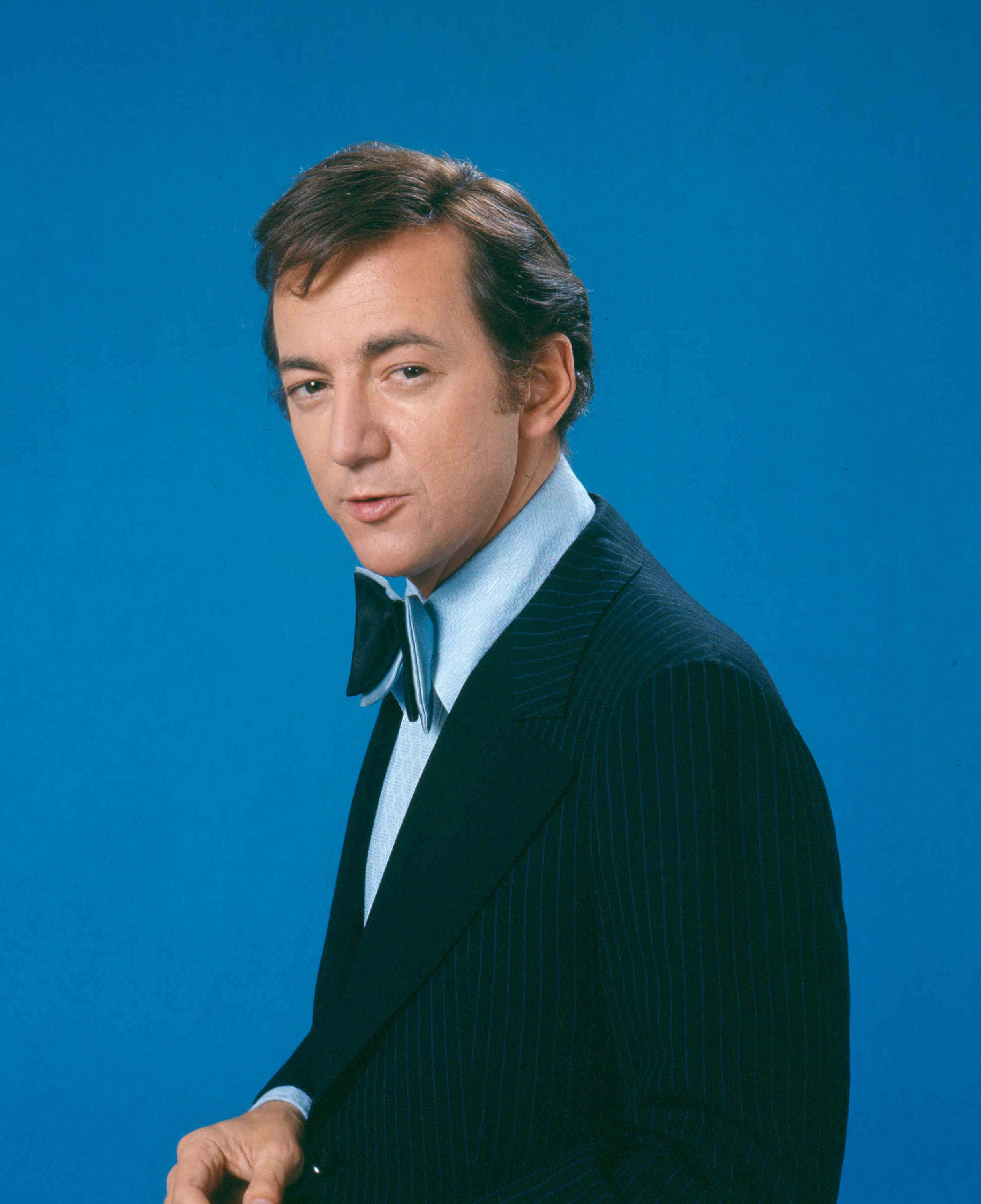 US singer and actor, wearing a dark blue pin-striped jacket, a light blue shirt and dark blue bowtie in a studio portrait, against a blue background, circa 1965 | Source:Getty Images