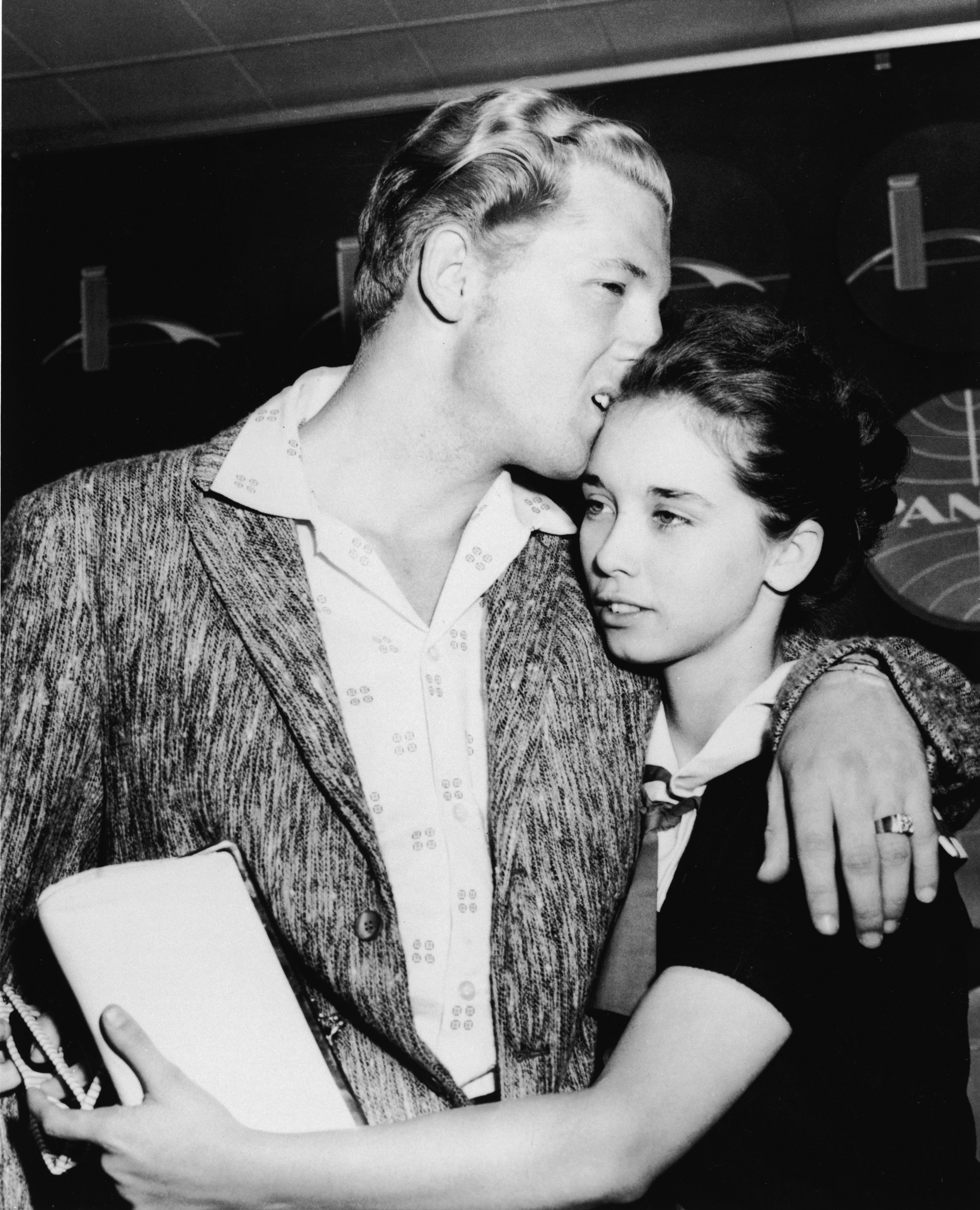 Jerry Lee Lewis hugs Myra Brown as they arrive in the airport from London after his tour of England was canceled, New York, May 28, 1958. | Source: Getty Images