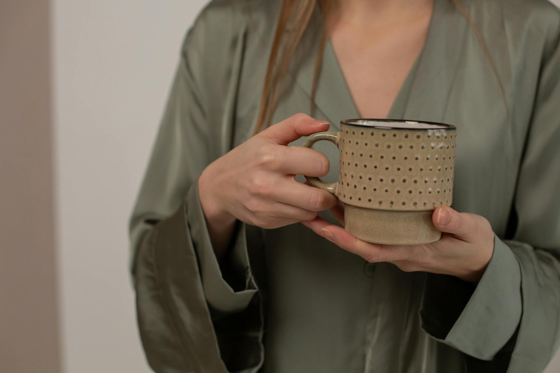 A woman holding a ceramic mug | Source: Pexels