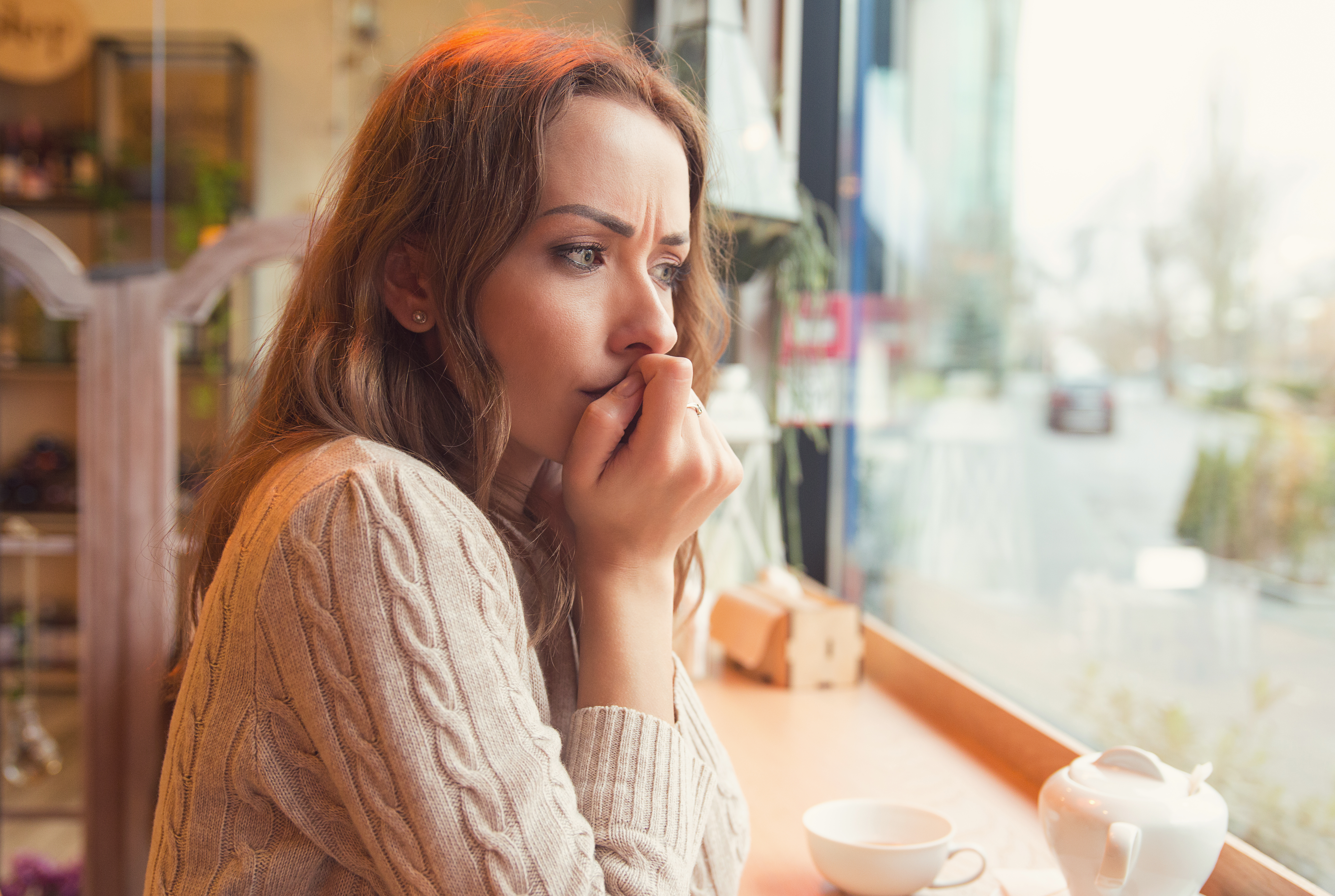A nervous young woman at a coffee shop | Source: Shutterstock