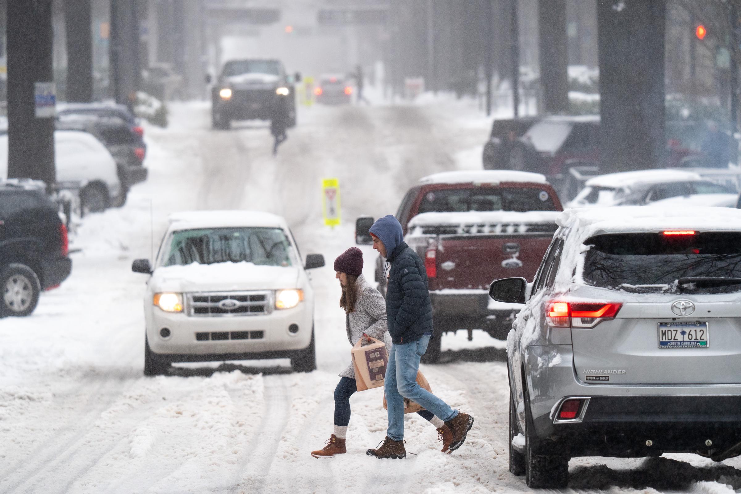 Pedestrians cross the street through the snow in South Carolina, on January 16, 2022 | Source: Getty Imahges