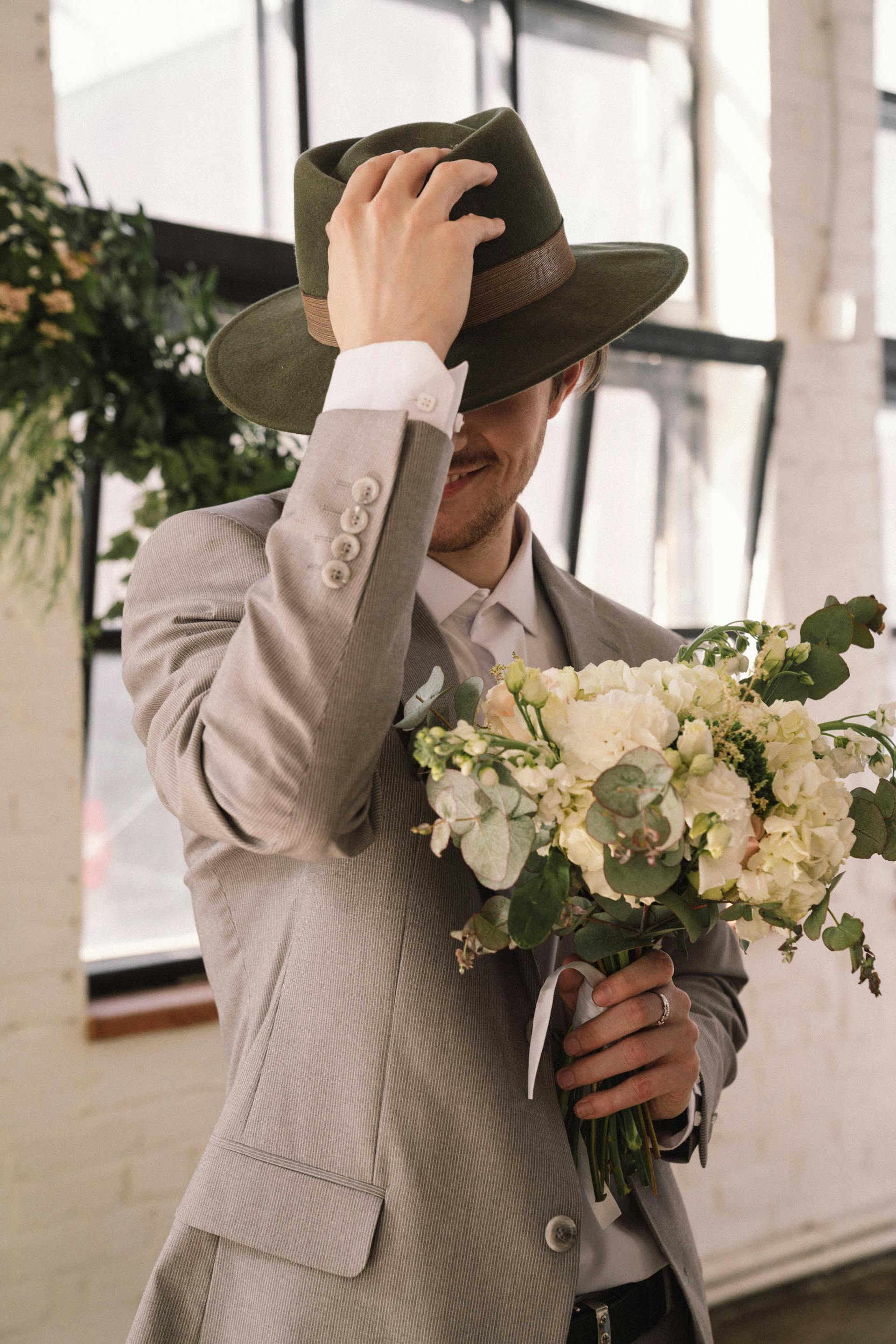 Man in a gray suit and hat holding flowers | Source: Pexels