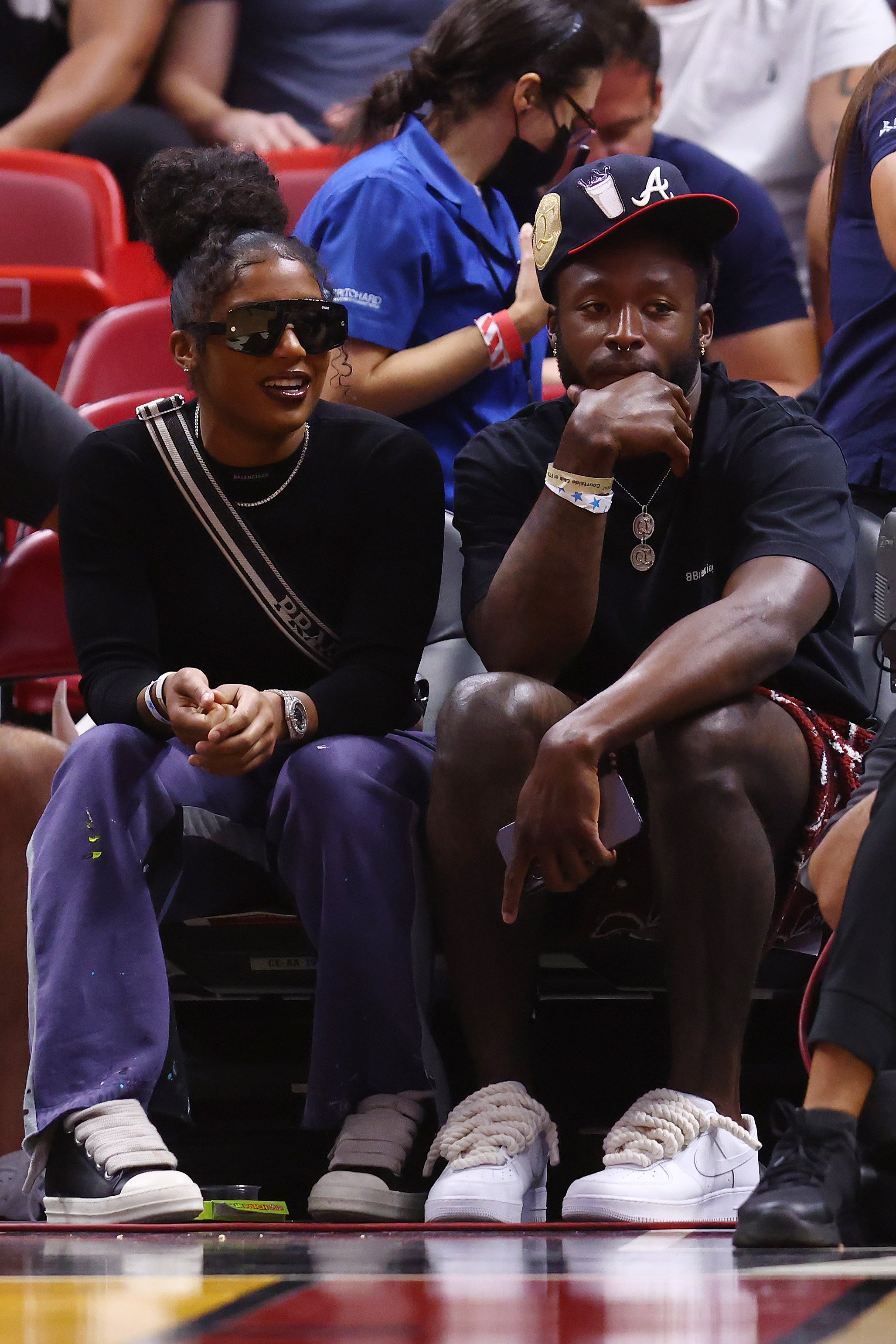 Te'a Cooper of the Los Angeles Sparks and Alvin Kamara of the New Orleans Saints look on during the second half between the Miami Heat and the Atlanta Hawks at FTX Arena, on April 8, 2022, in Miami, Florida. | Source: Getty Images