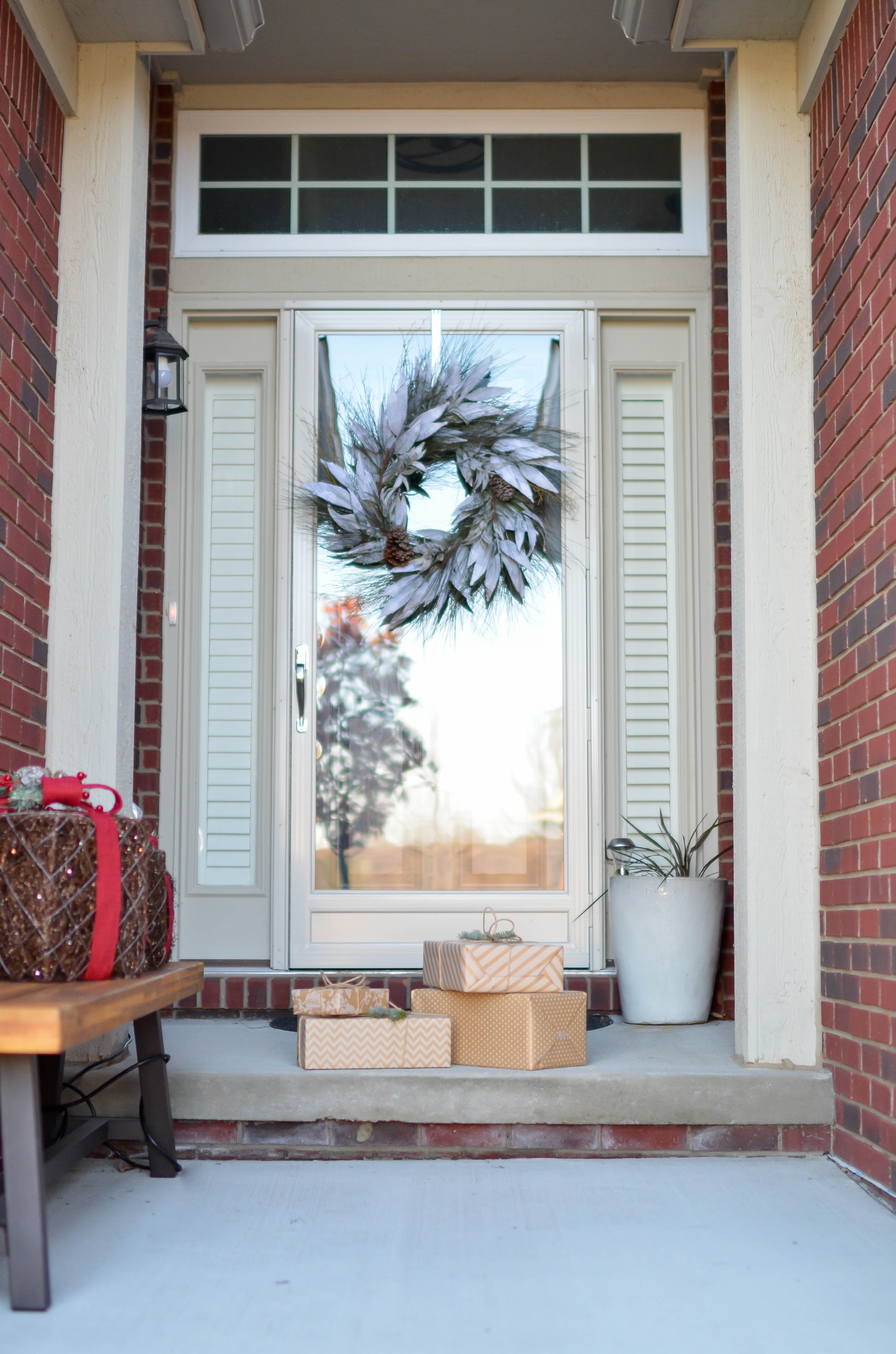 Four brown gift boxes near a glass paneled door with wreath. | Source: Pexels