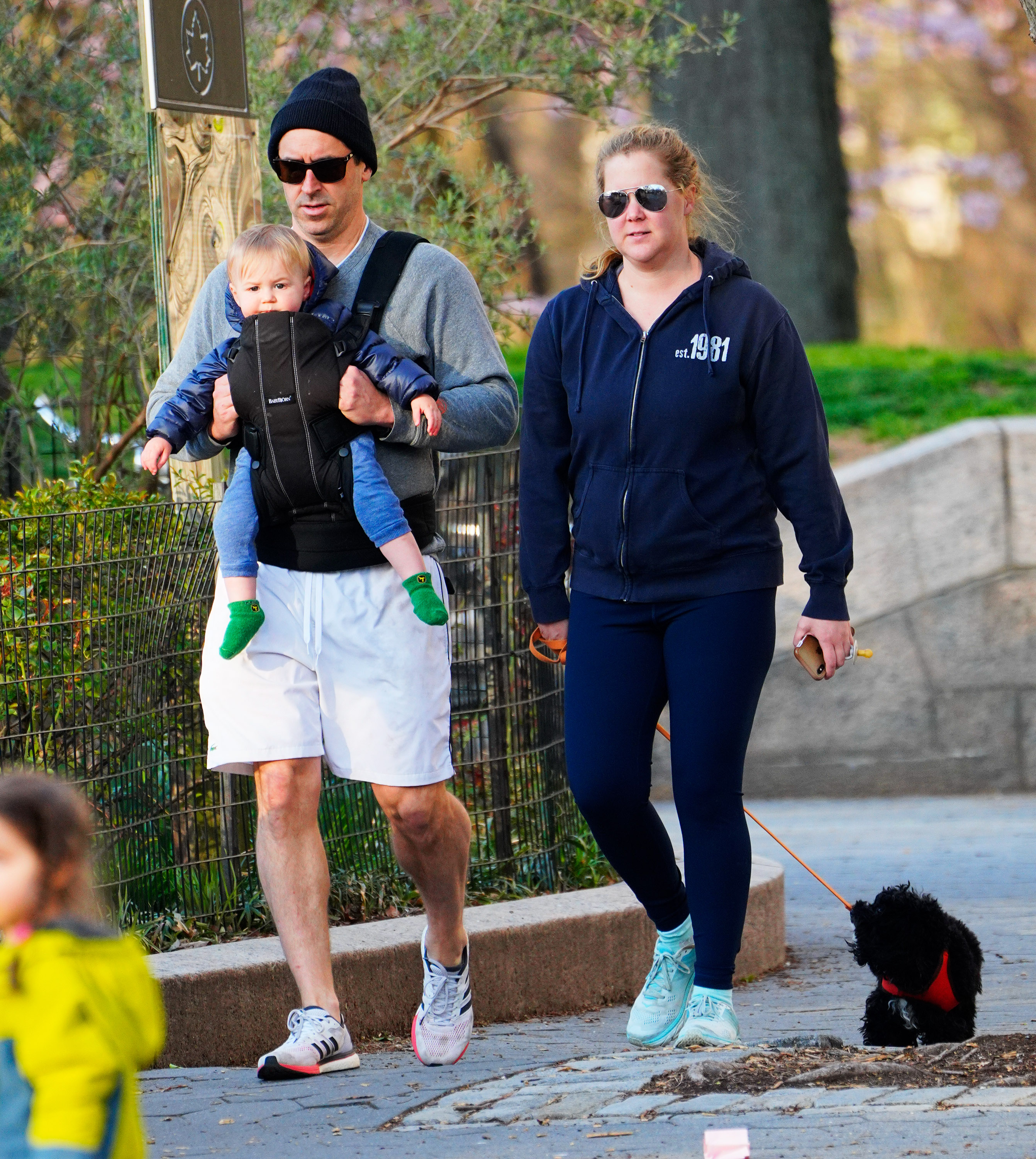 Amy Schumer looked casual and noticeably fuller-faced as she enjoyed a family stroll with husband Chris Fischer, their young son Gene, and the family dog in New York City on April 1, 2020. Wearing navy leggings and a zip-up hoodie, the comedian's figure appeared rounder and less defined than in her recent bikini posts, reflecting a different stage in her post-pregnancy journey.