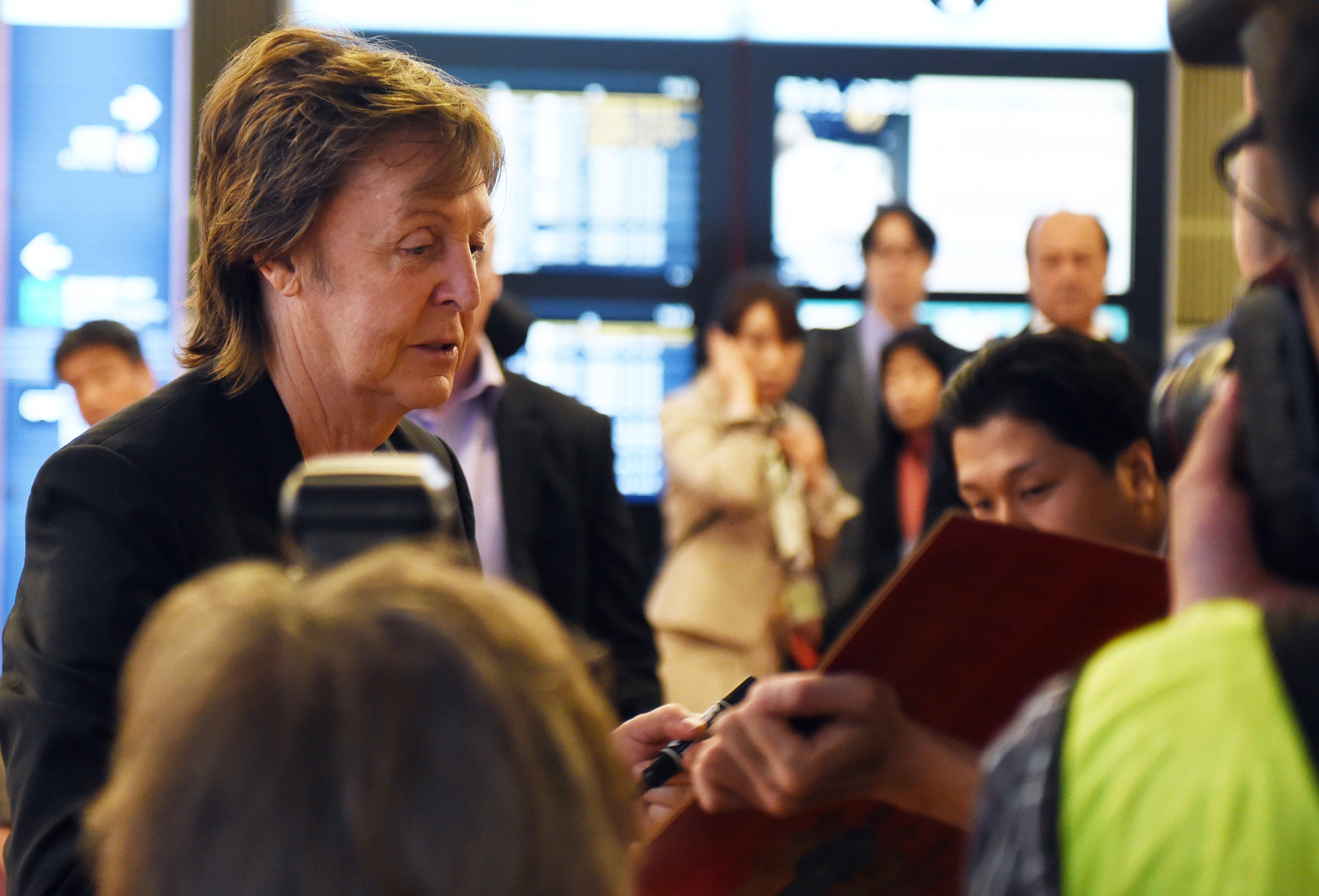 Paul McCartney signs his autograph to fans upon his arrival at the Haneda airport in Tokyo on May 15, 2014. | Source: Getty Images