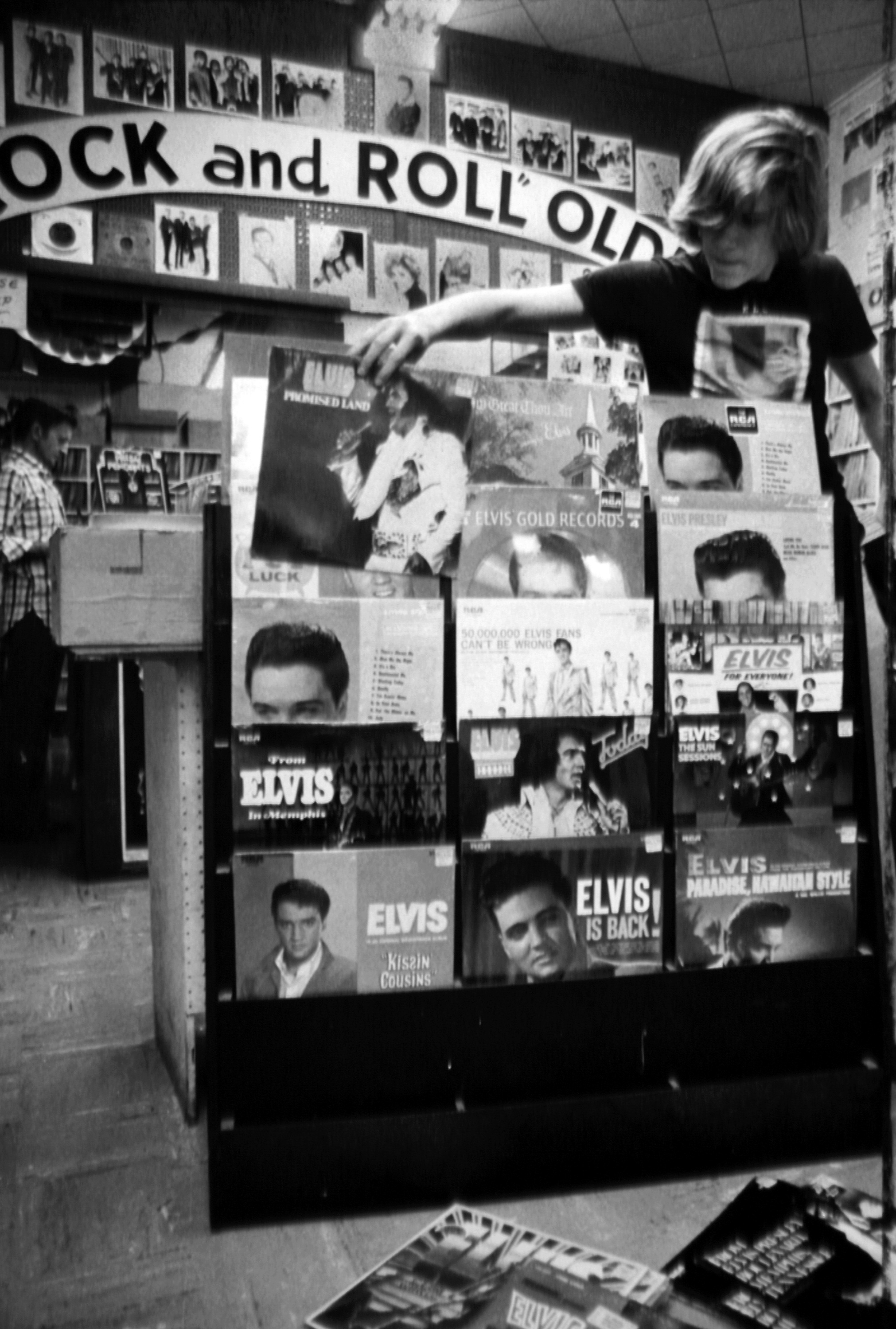 A store clerk arranging a display of Elvis Presley records at a music store on August 17, 1977. | Source: Getty Images
