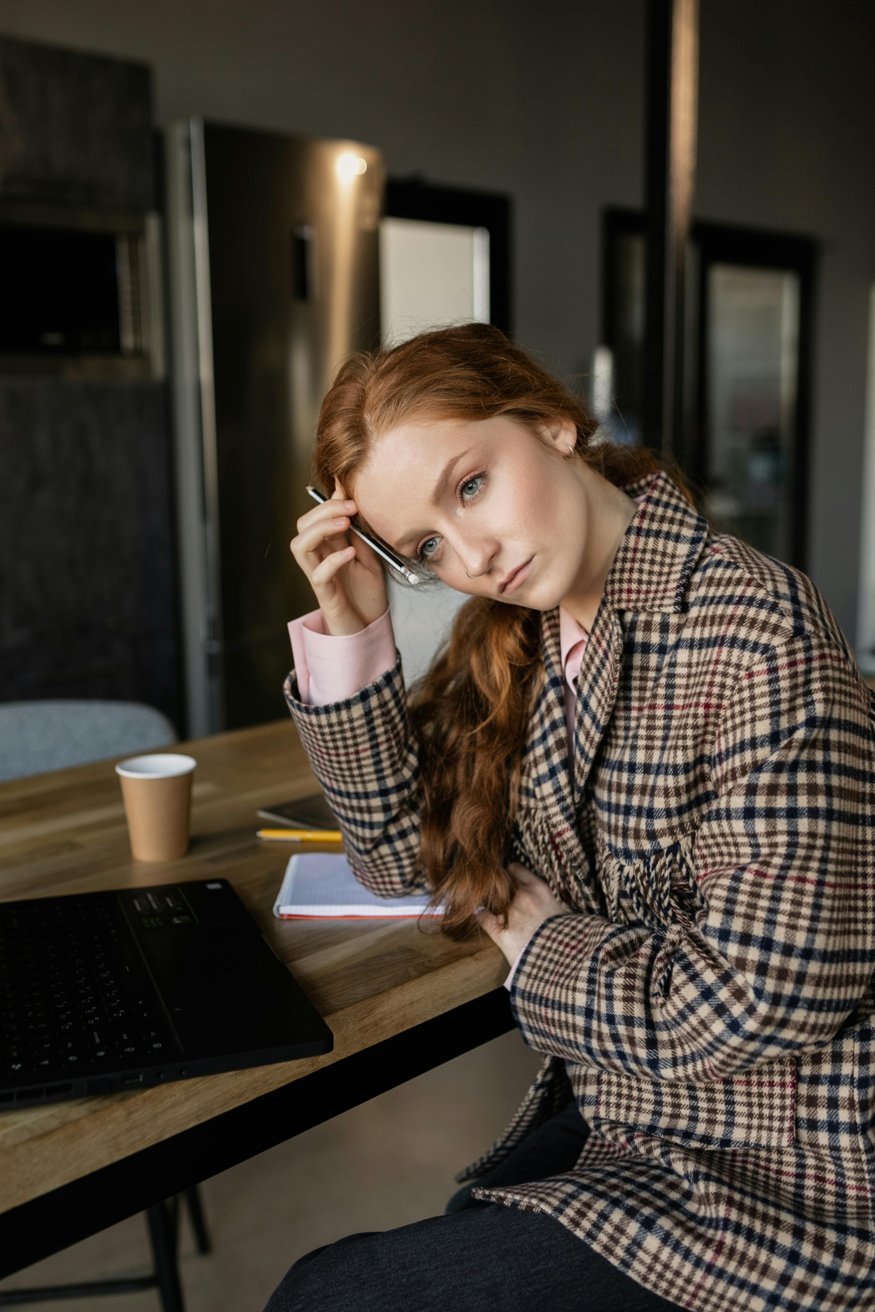 A worried woman in brown suit sitting at a table | Source: Pexels