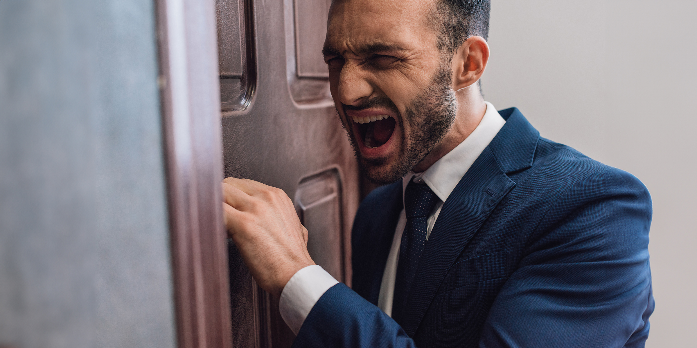 An angry man knocking on a door | Source: Shutterstock