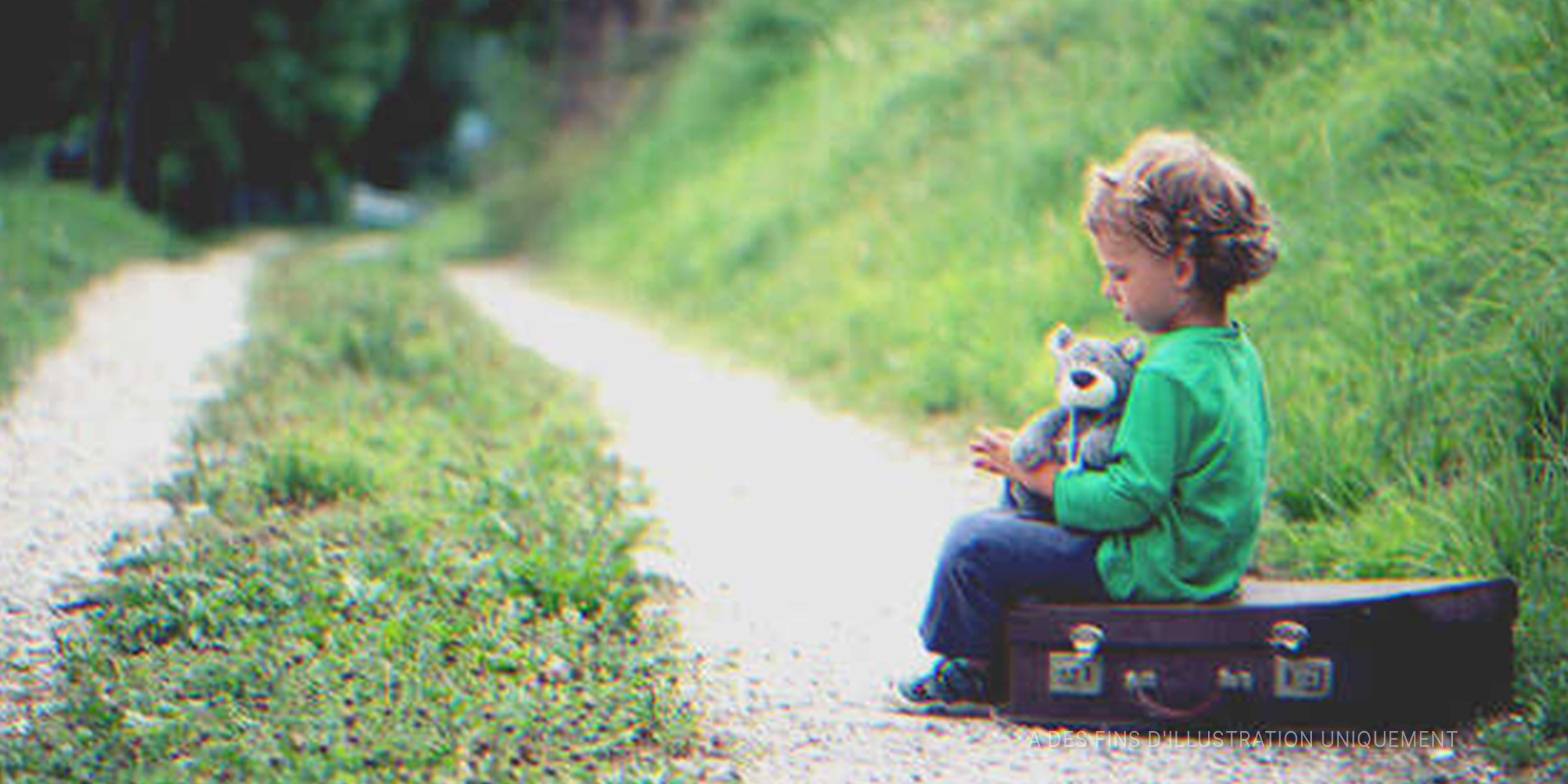Un enfant assis sur une valise | Photo : Shutterstock