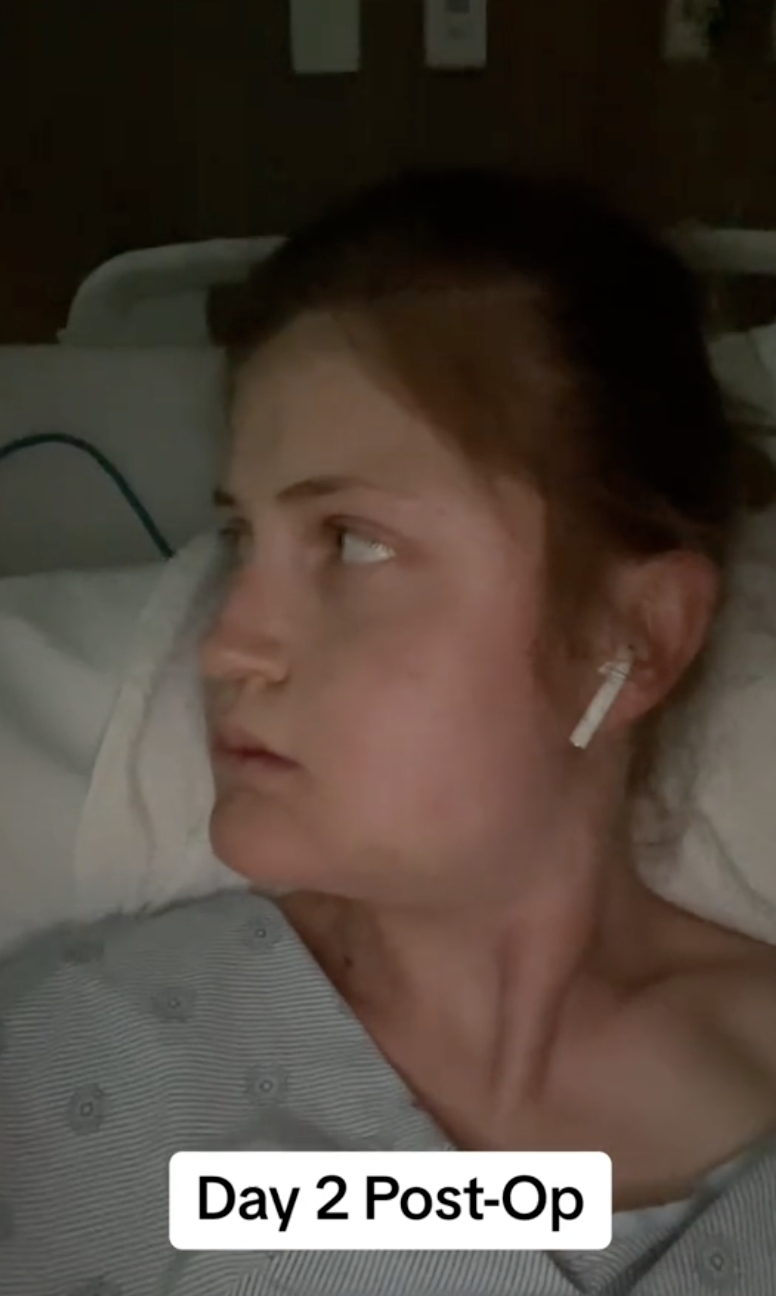 Wearing a hospital gown and AirPod, Virginia Elder gazes sideways during her second day of healing. | Source: TikTok/virginiaeelder