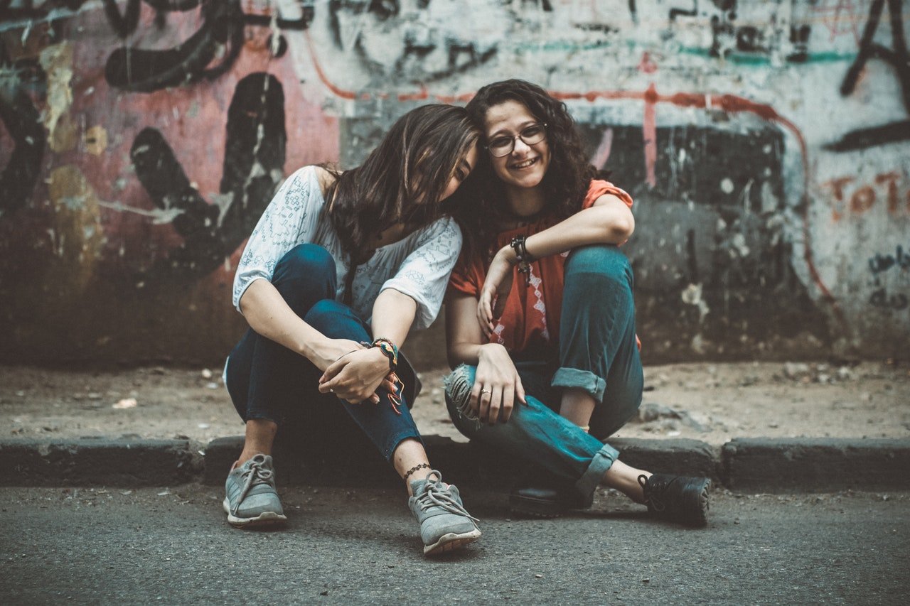 Photo of two ladies sitting by the road | Photo: Pexels