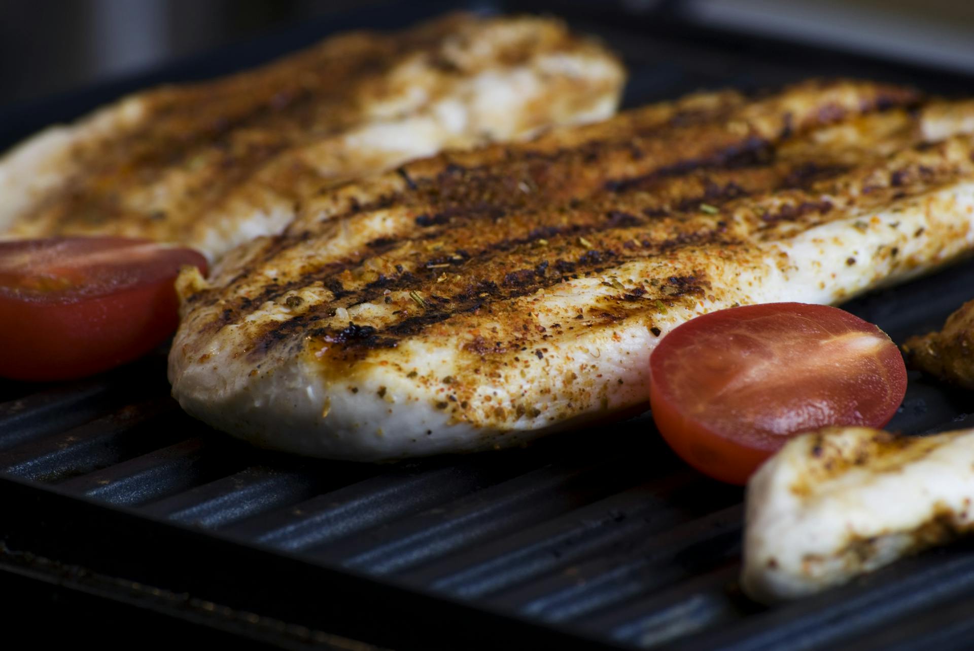 Slices of meat and tomatoes on a grill | Source: Pexels