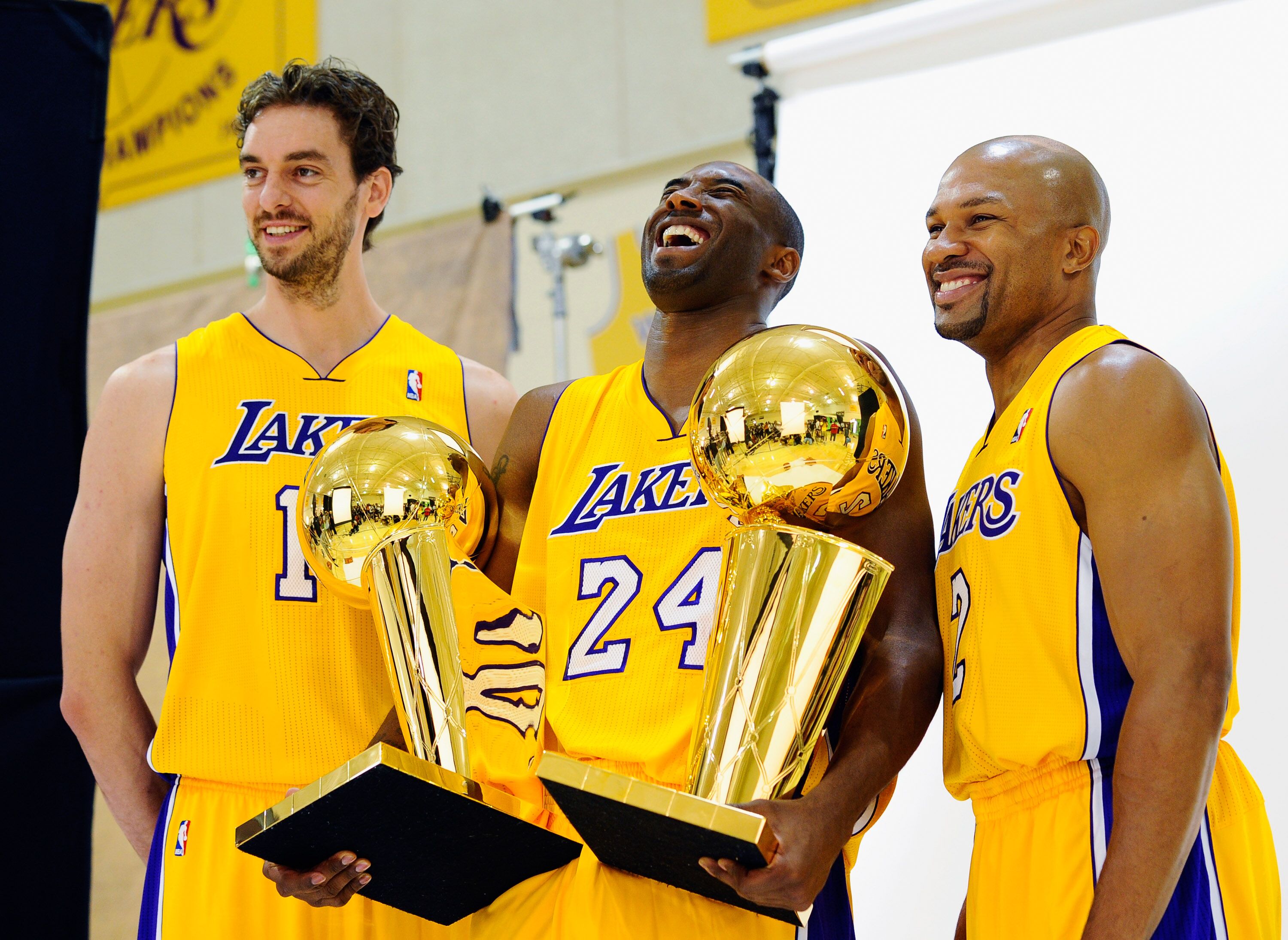 Kobe Bryant #24 of the Los Angeles Lakers laughs as he holds two NBA Finals Larry O'Brien Championship Trophy's as he poses for a photograph. | Source: Getty Images