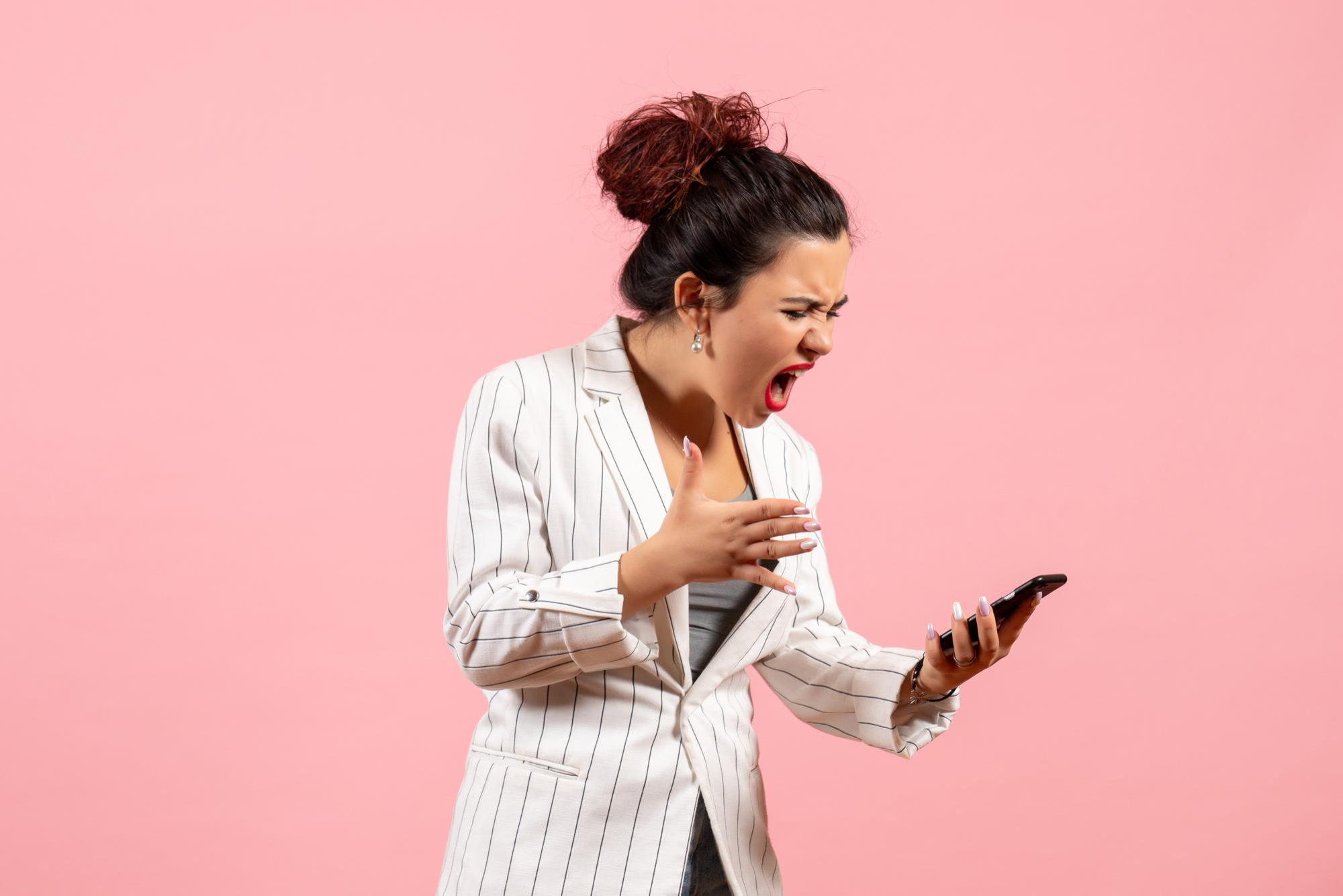 An upset woman reacting badly to something on a phone | Source: Freepik