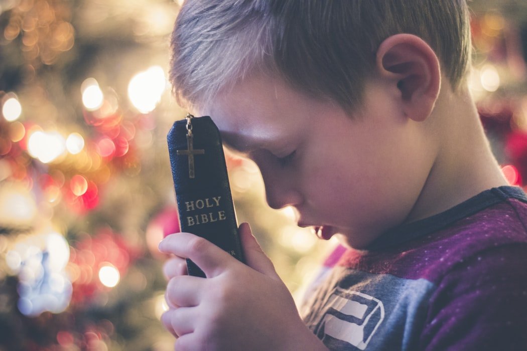 Niño con una Biblia. | Foto: Unsplash.