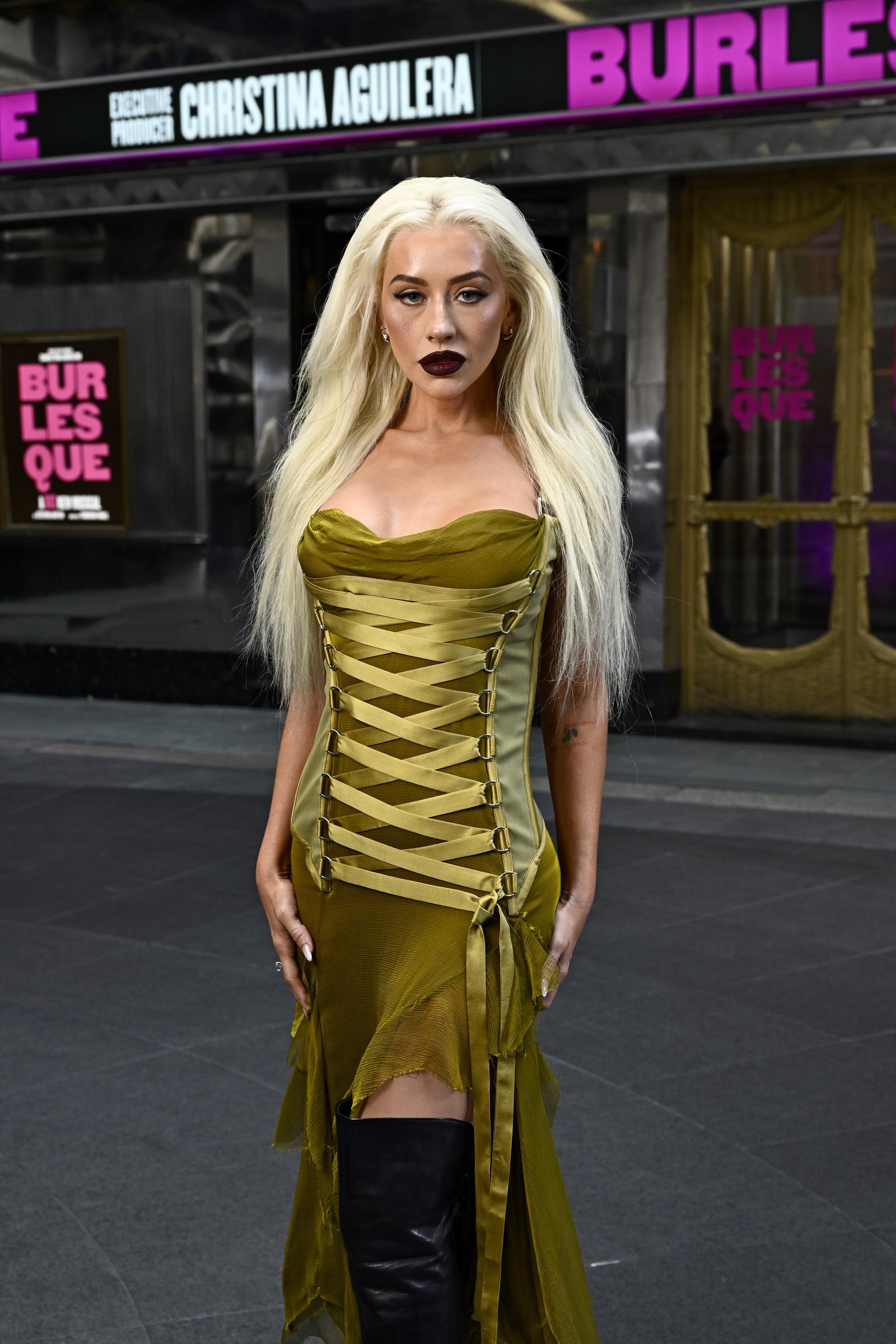 With a confident stance and hands at her sides, Christina Aguilera's final pose emphasizes the structural design of her dress and the gathered fabric layers. Her monochromatic outfit is punctuated by sharp black boots, drawing attention to the edgy-meets-elegant aesthetic she brought to the event.