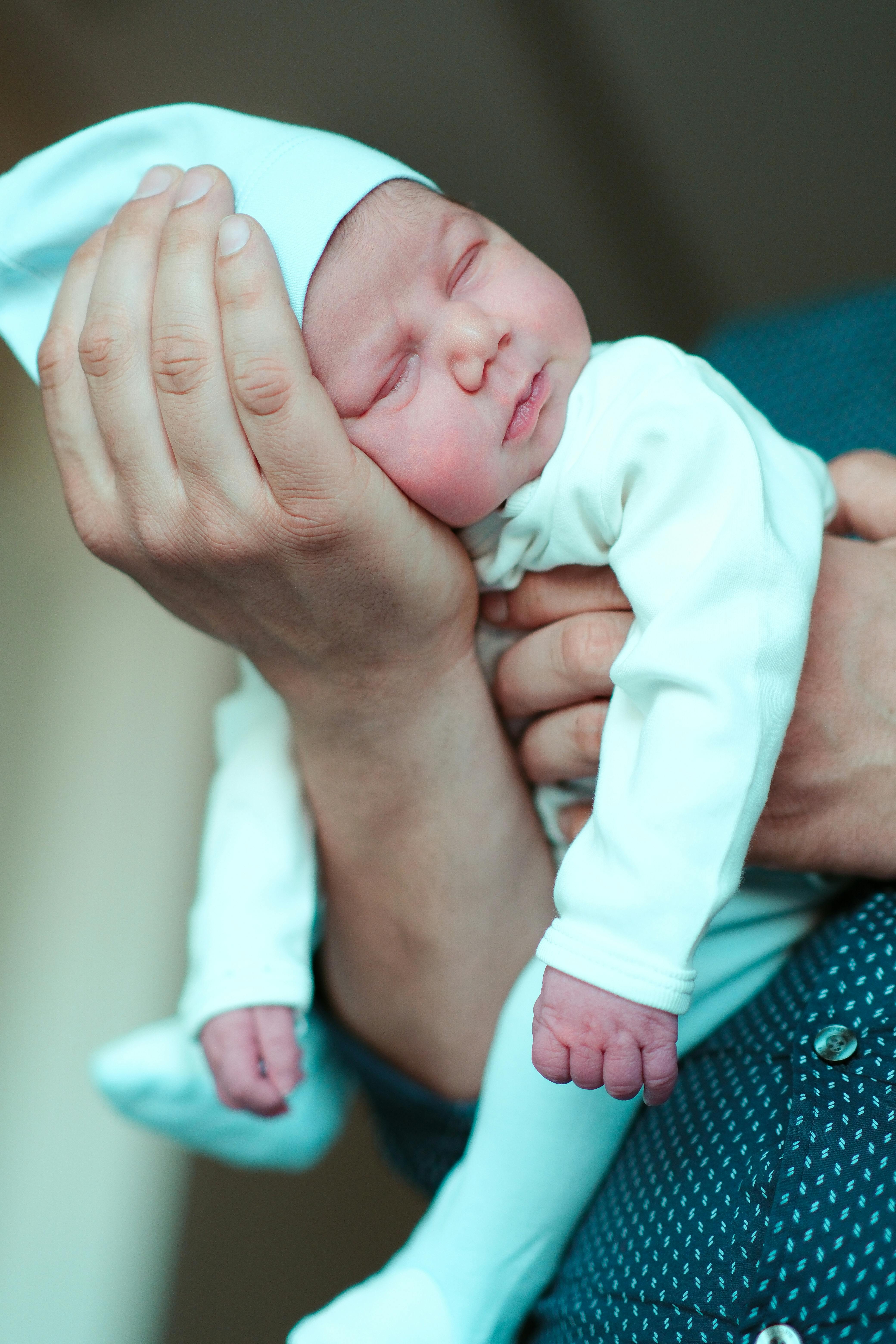 A sleeping baby in a man's arms | Source: Pexels