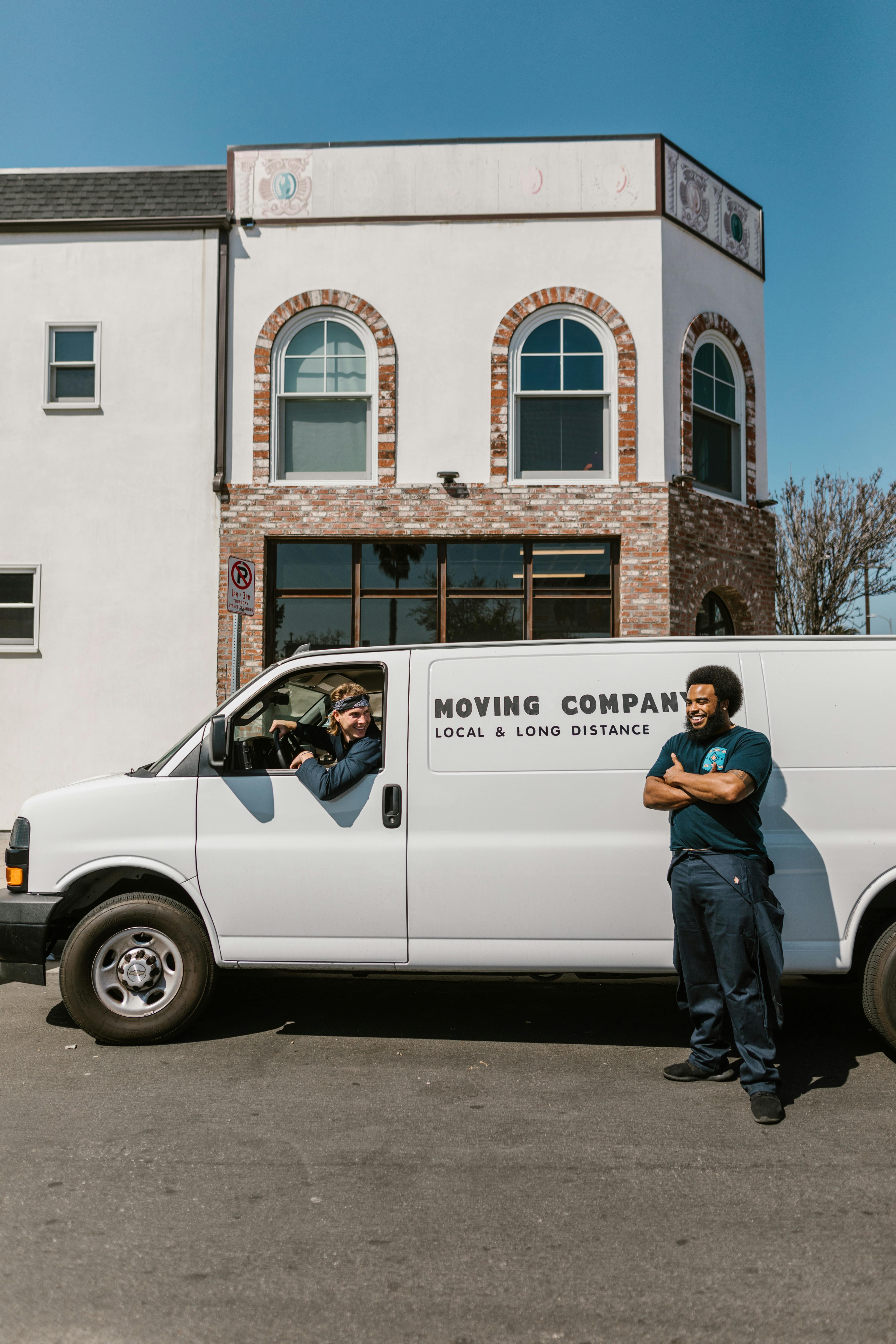 A person standing beside a moving truck while a man is sitting inside it | Source: Pexels