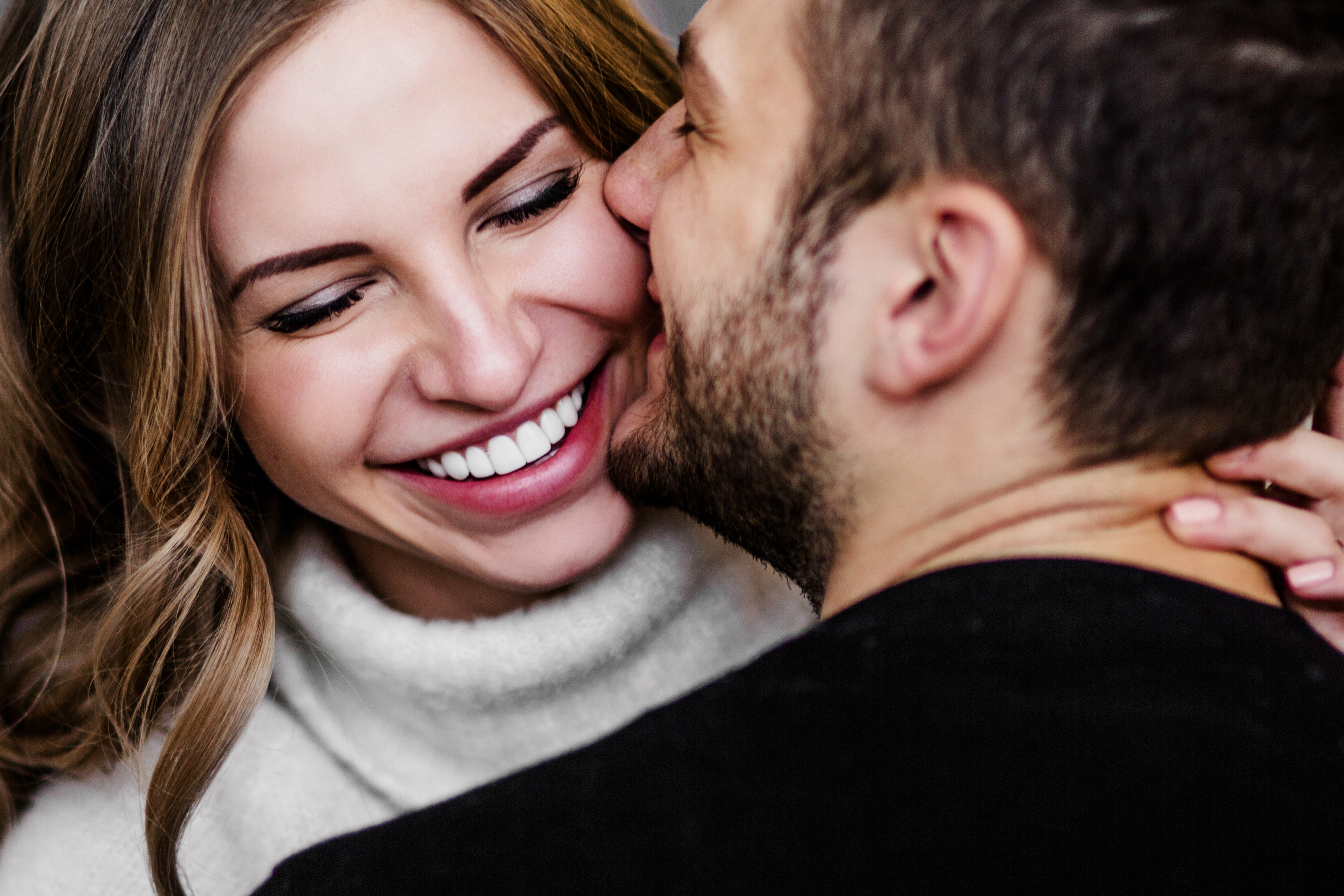 A man kissing a woman on the cheek as she smiles | Source: Shutterstock
