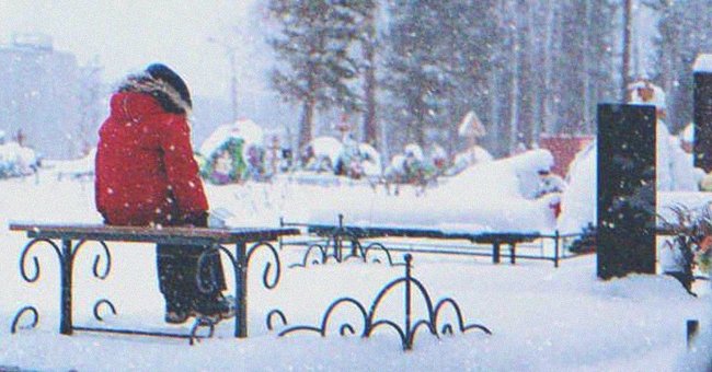 A kid sitting on a graveyard's bench in a snowy day | Source: Shutterstock