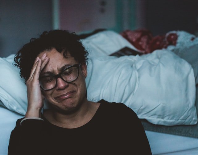 A photo of a woman crying by her bedside. | Photo: Unspalsh