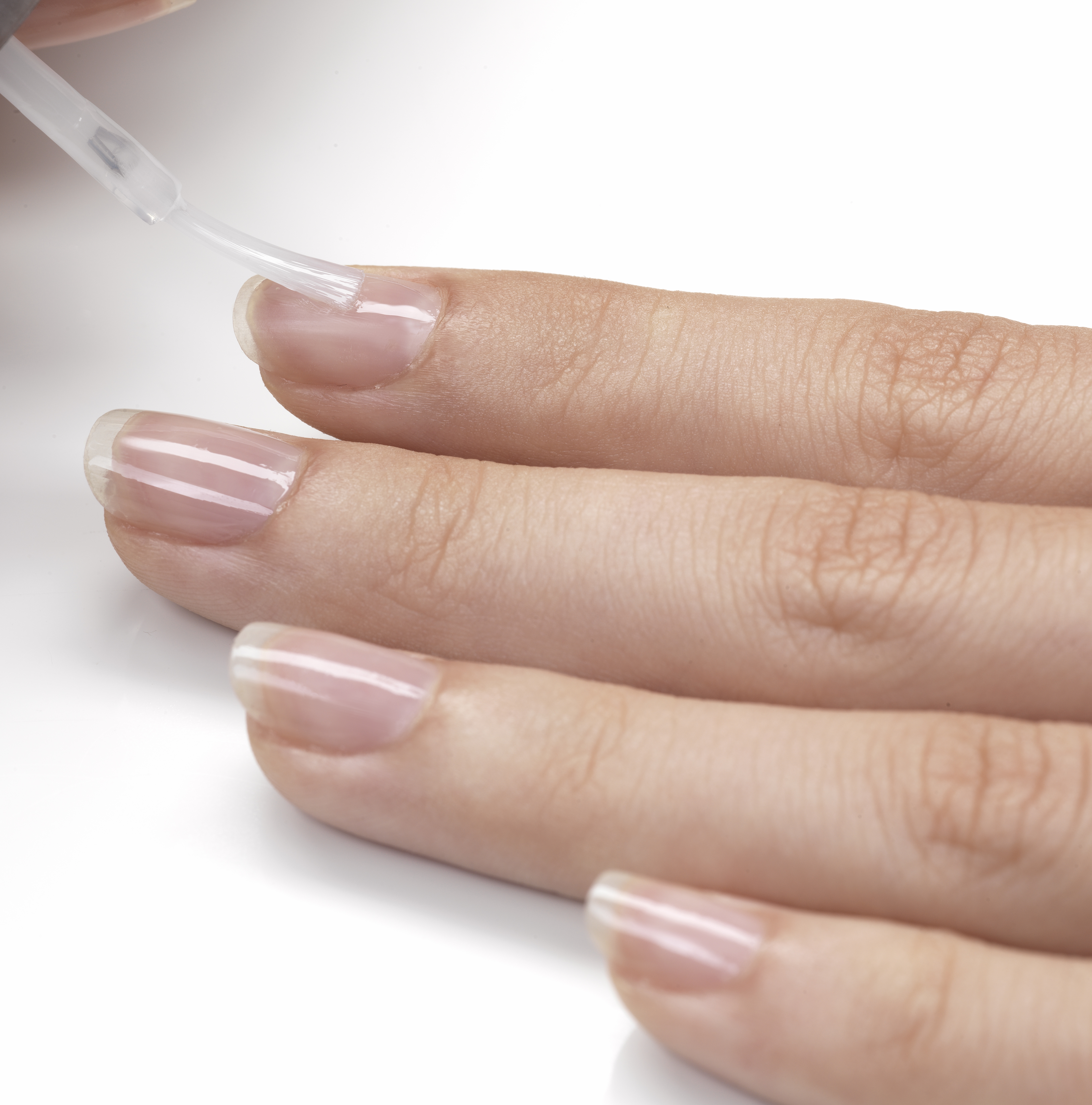 Applying base coat to nails | Source: Getty Images