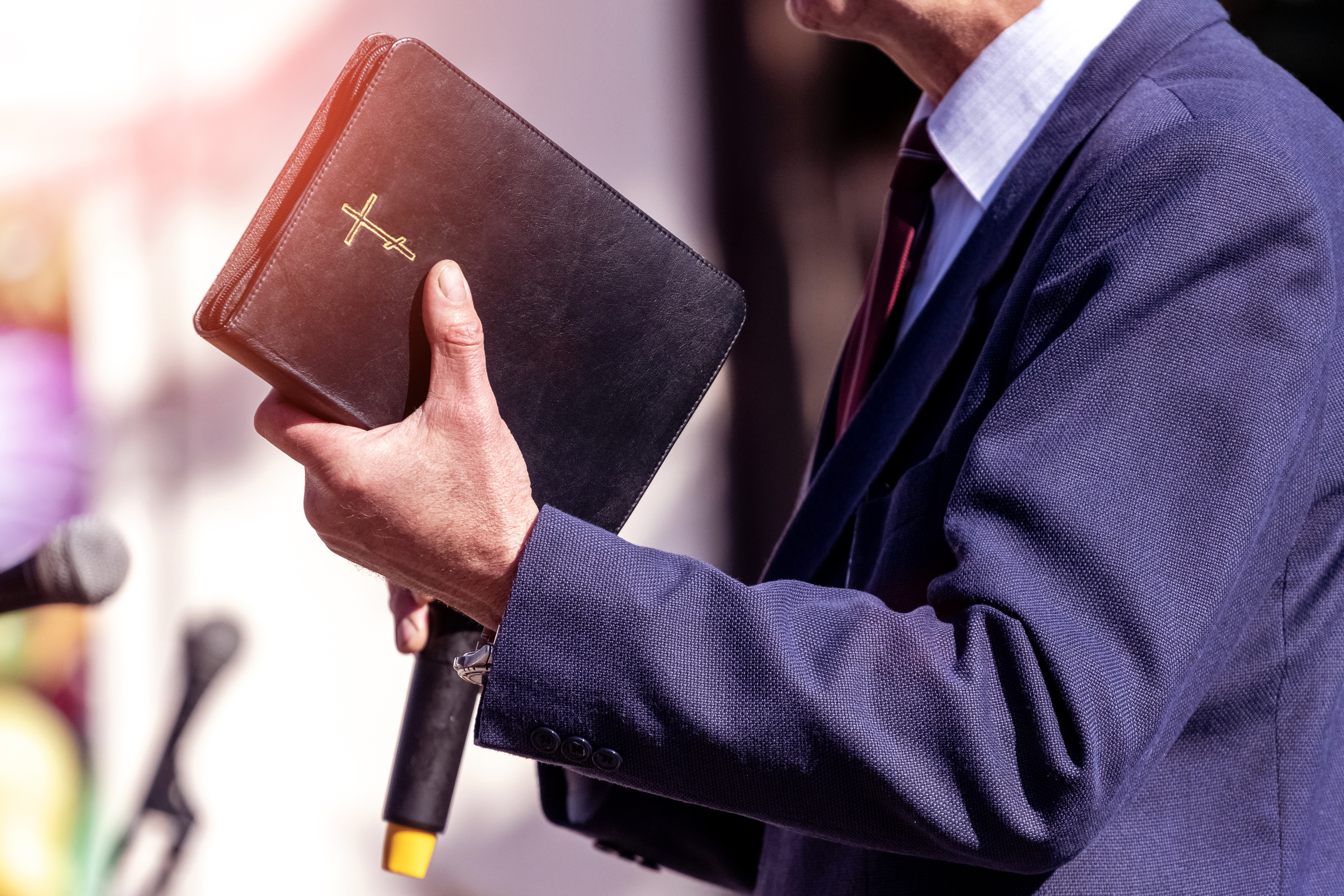 A pastor holding his Bible during a sermon | Source: Shutterstock