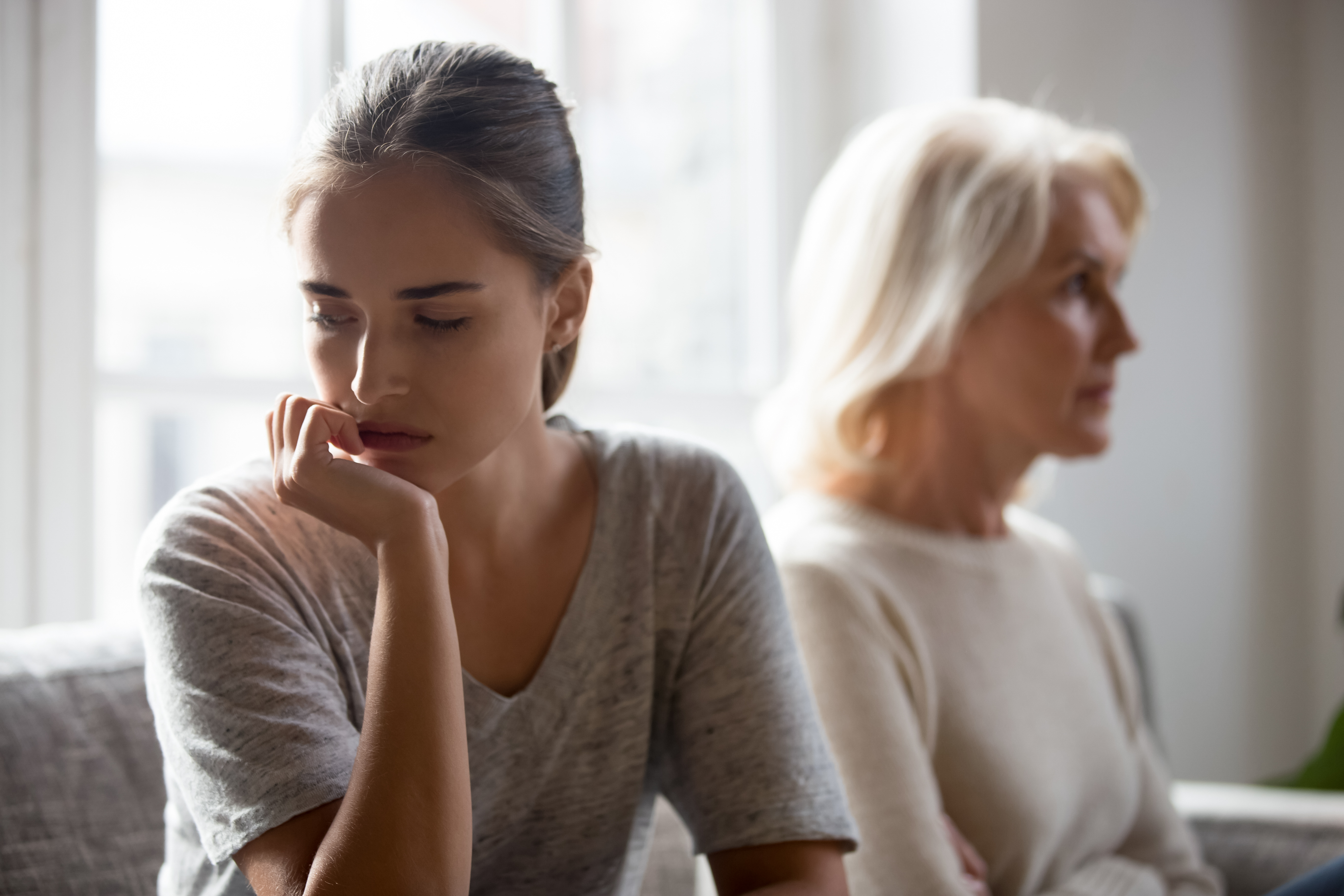 An upset younger woman sitting next to an older woman | Source: Shutterstock