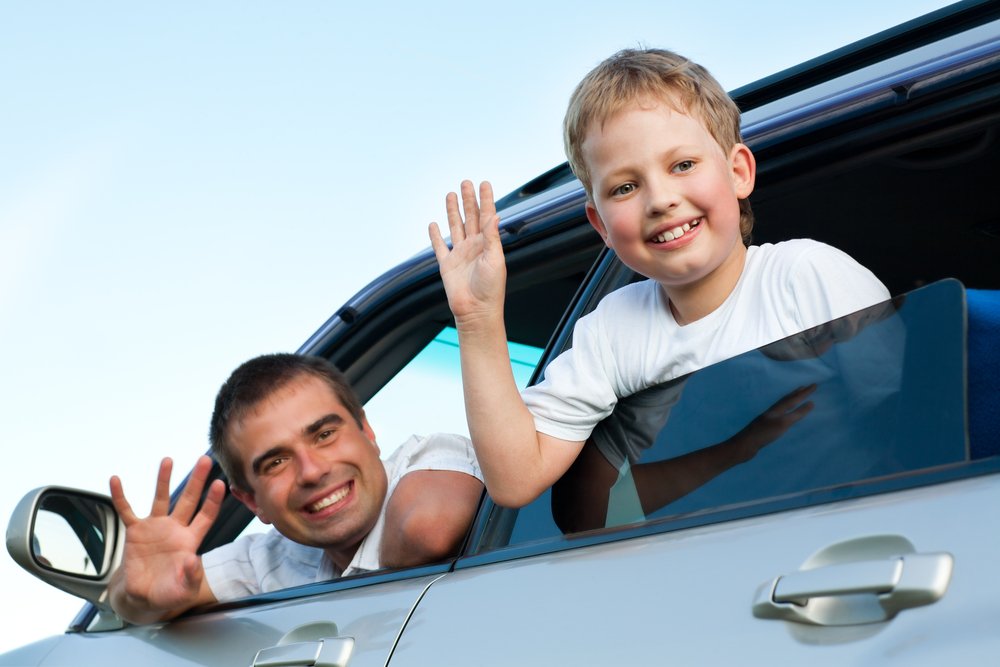 Padre e hijo saludando desde un automóvil. | Foto: Shutterstock