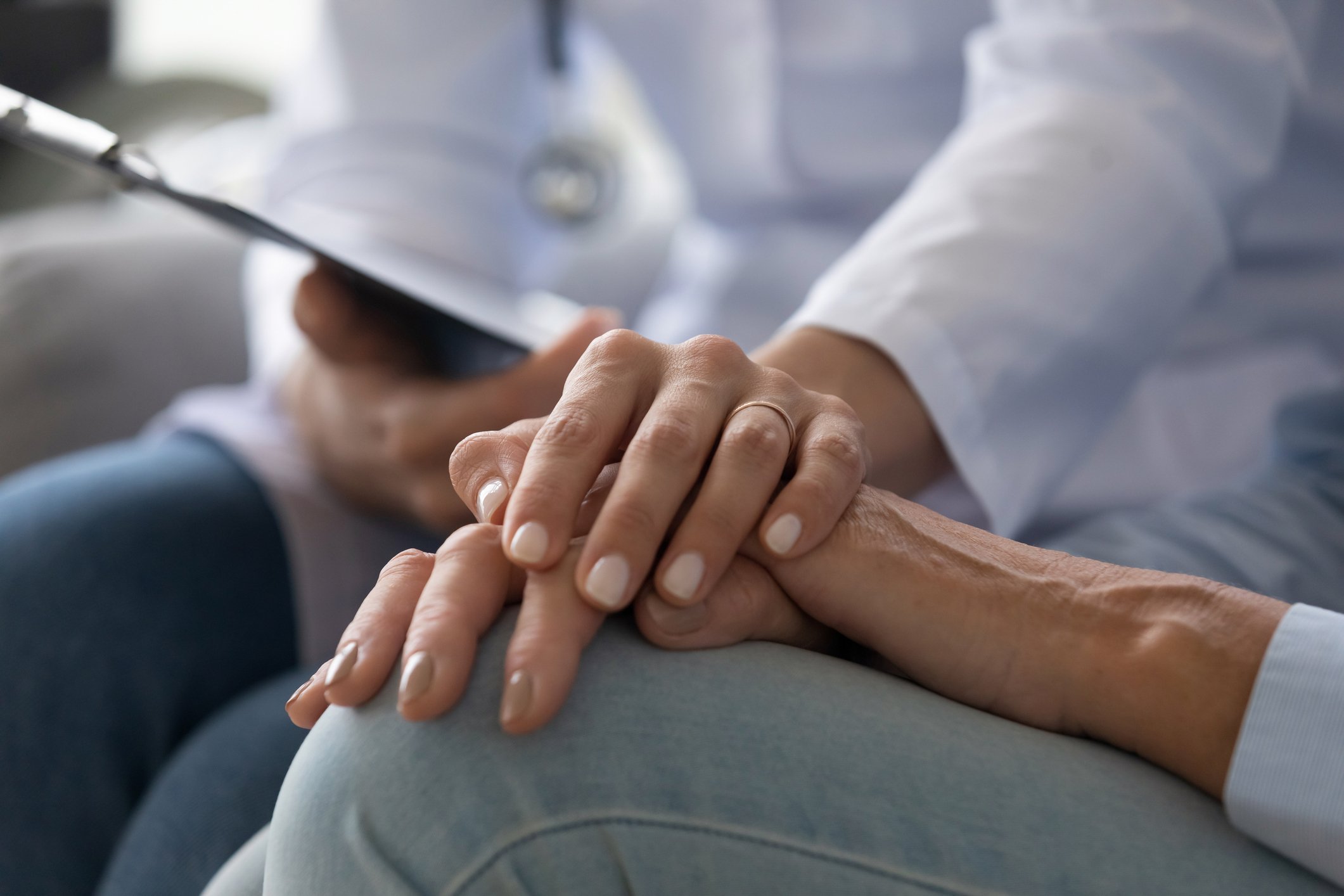 Junge Ärztin, die Hand einer älteren Patientin hält, Nahaufnahme | Quelle: Getty Images