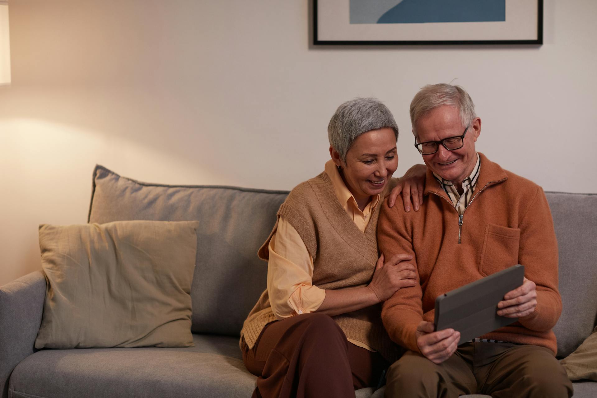 A senior man and woman smile while looking at a tablet computer | Source: Pexels