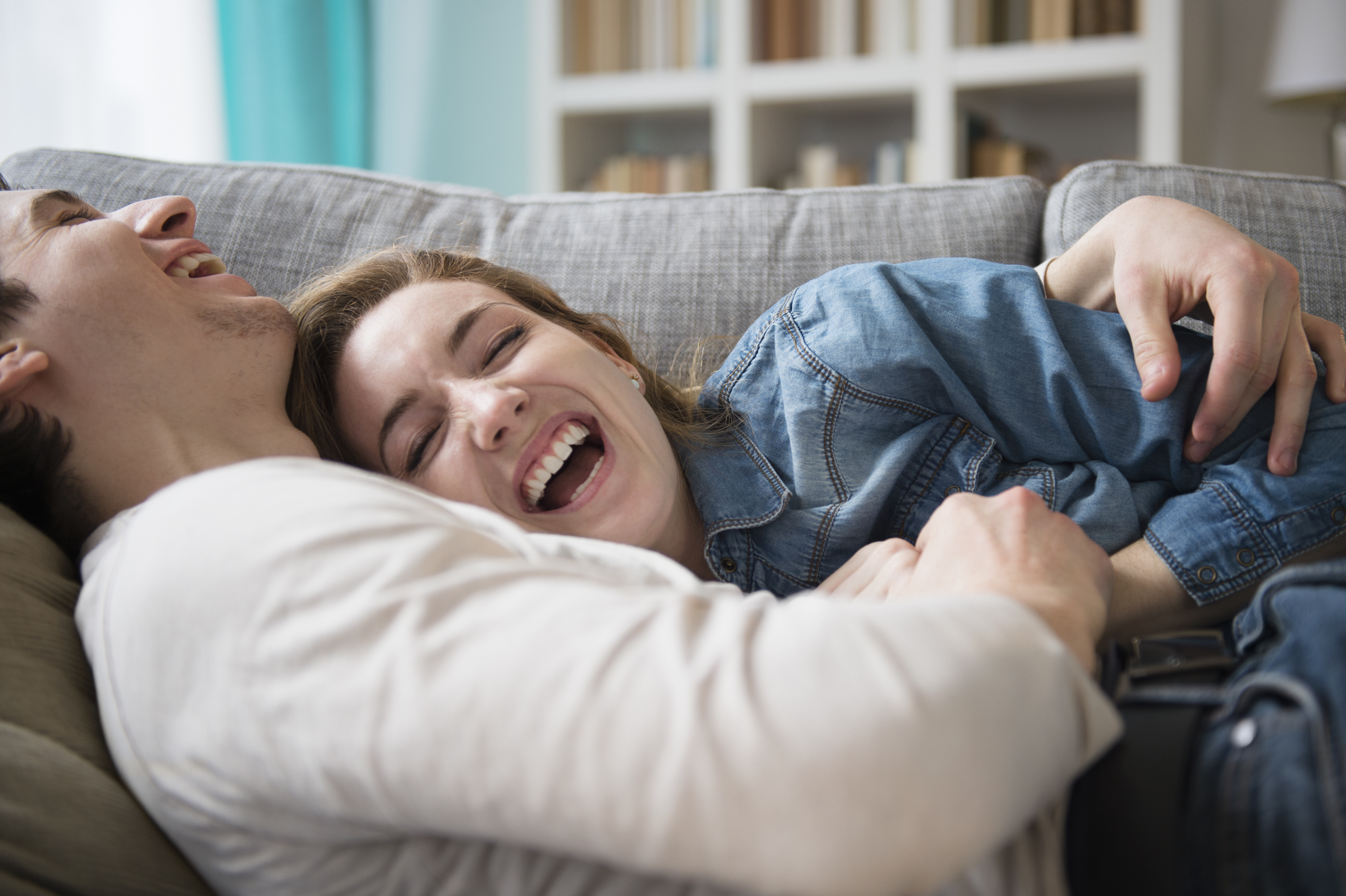 Couple laughing together on couch | Source: Getty Images