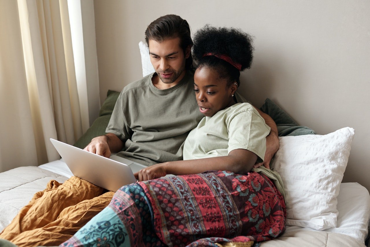 Photo of couple with a laptop in bed | Photo: Pexels
