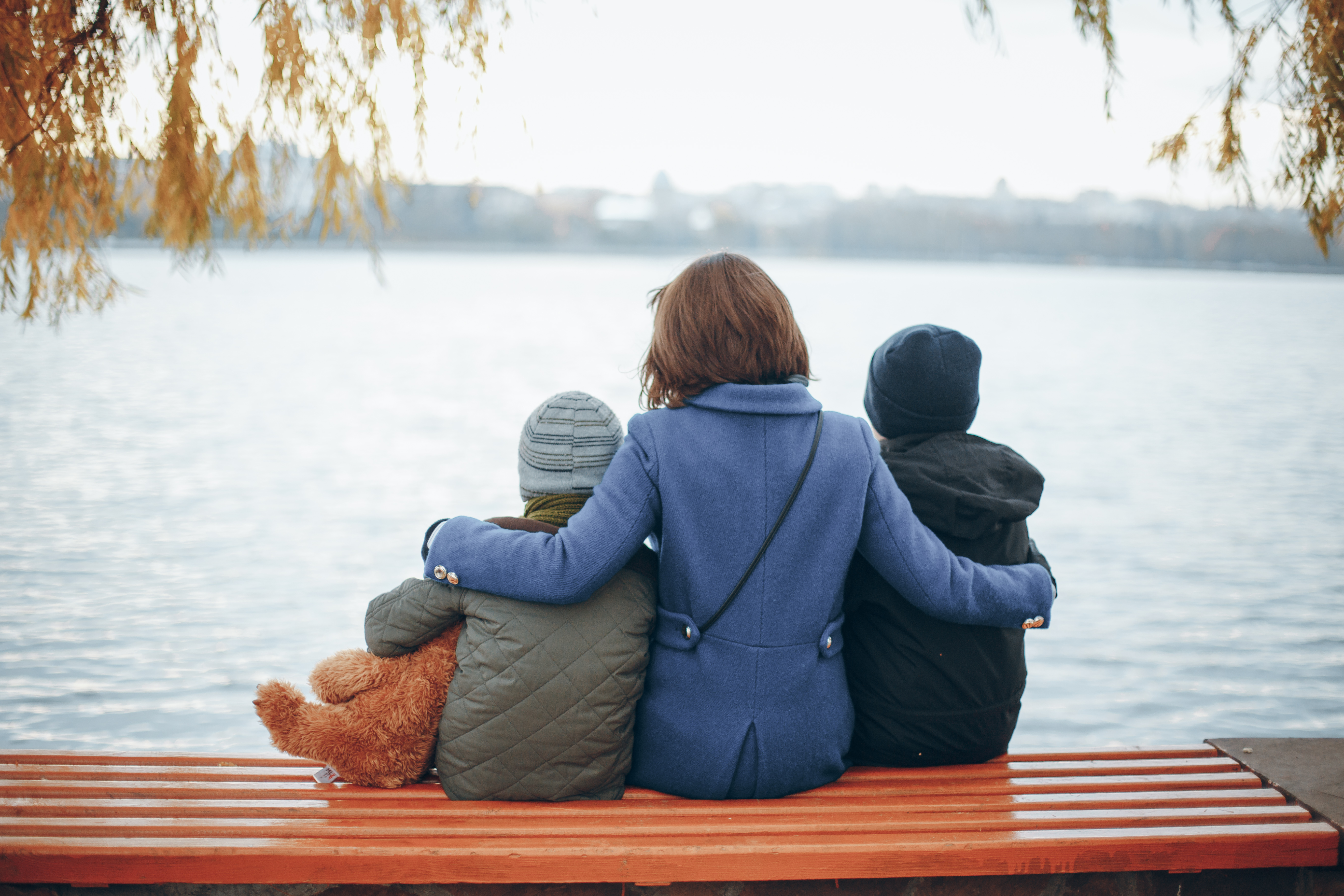 A woman sitting on a bench with two children | Source: Shutterstock