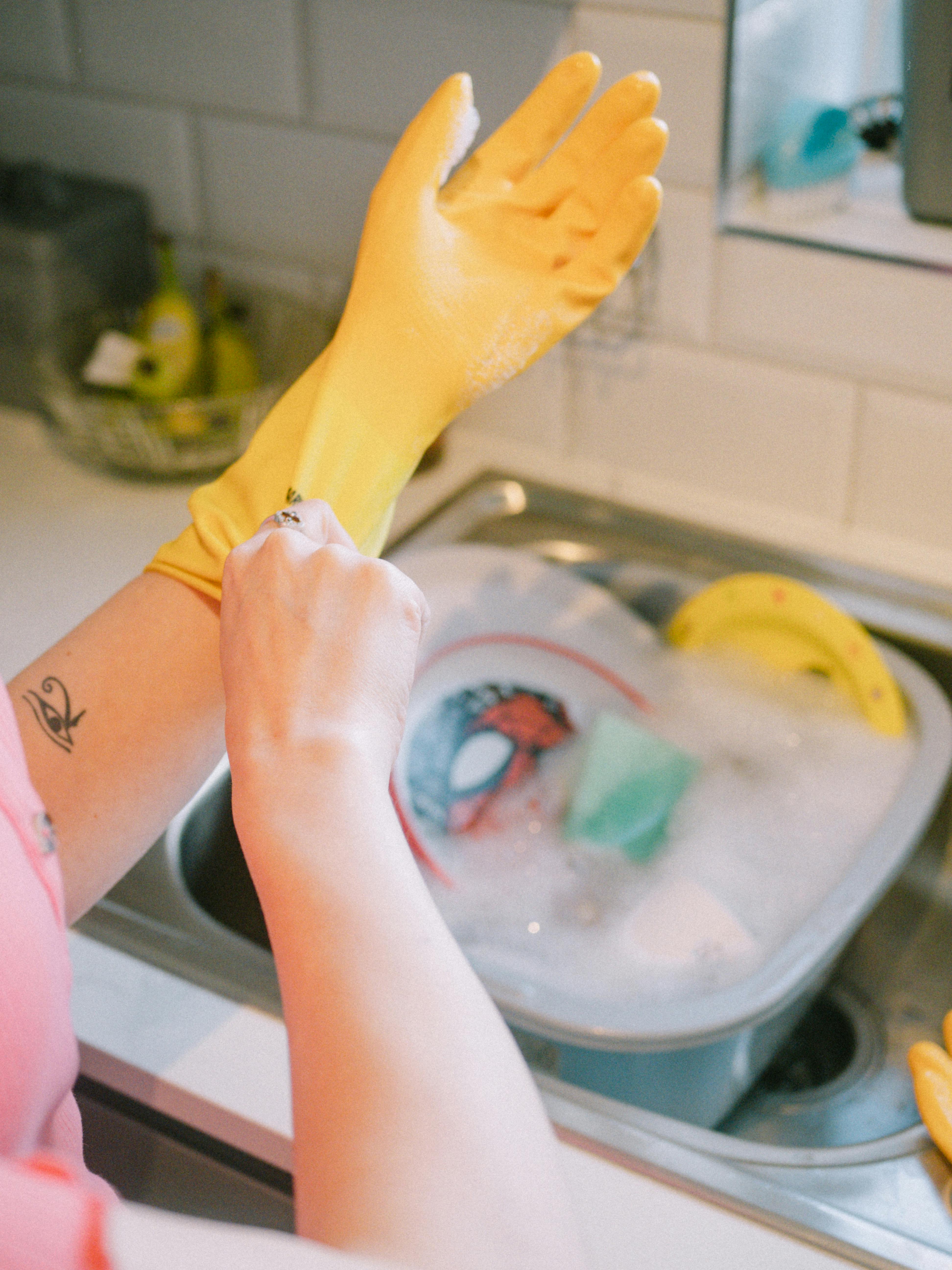 A woman wearing gloves ready to wash dishes | Source: Pexels