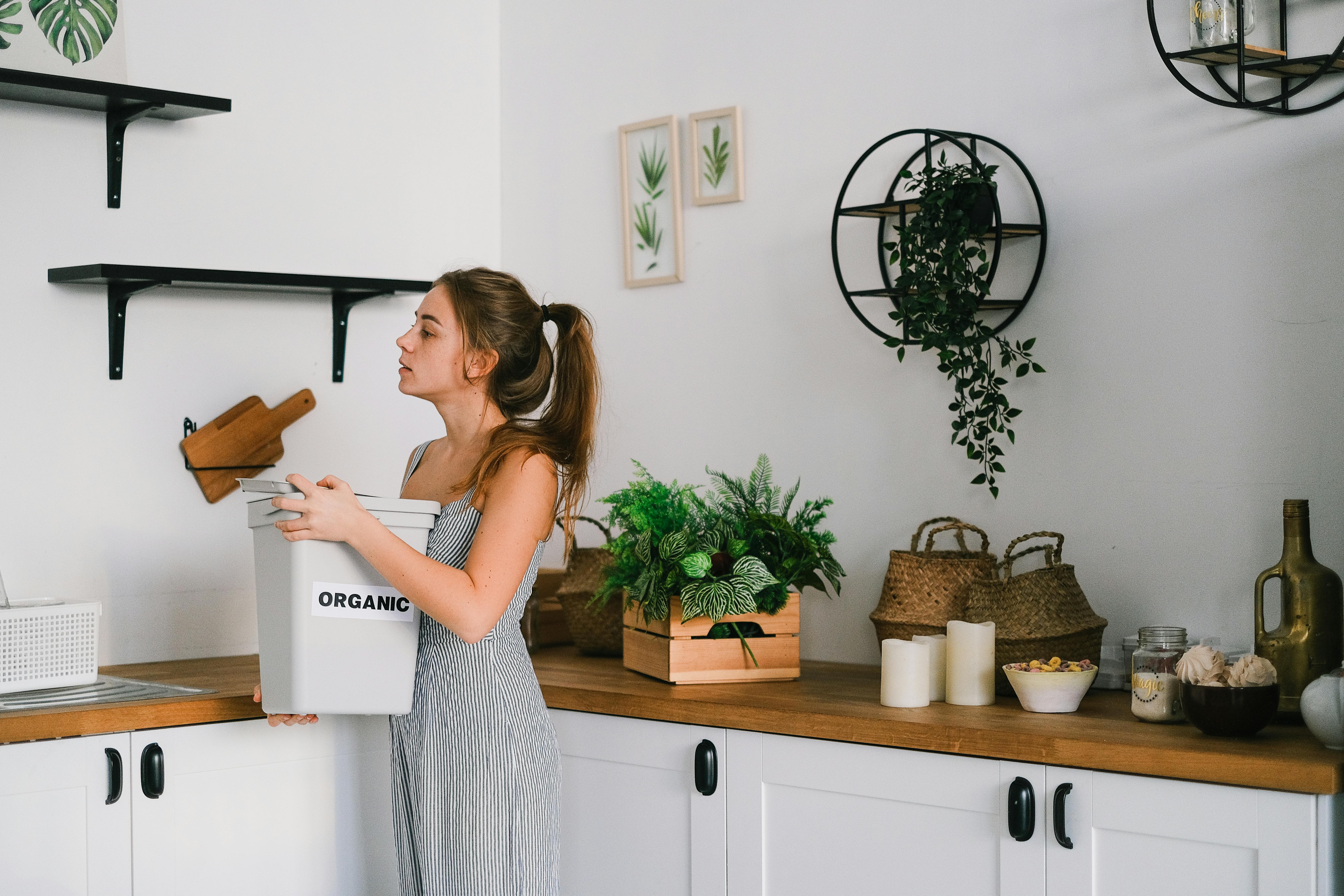 A woman carries an organic waste bin, underscoring the importance of regularly disinfecting bins to maintain a fresh-smelling home. | Source: Pexels