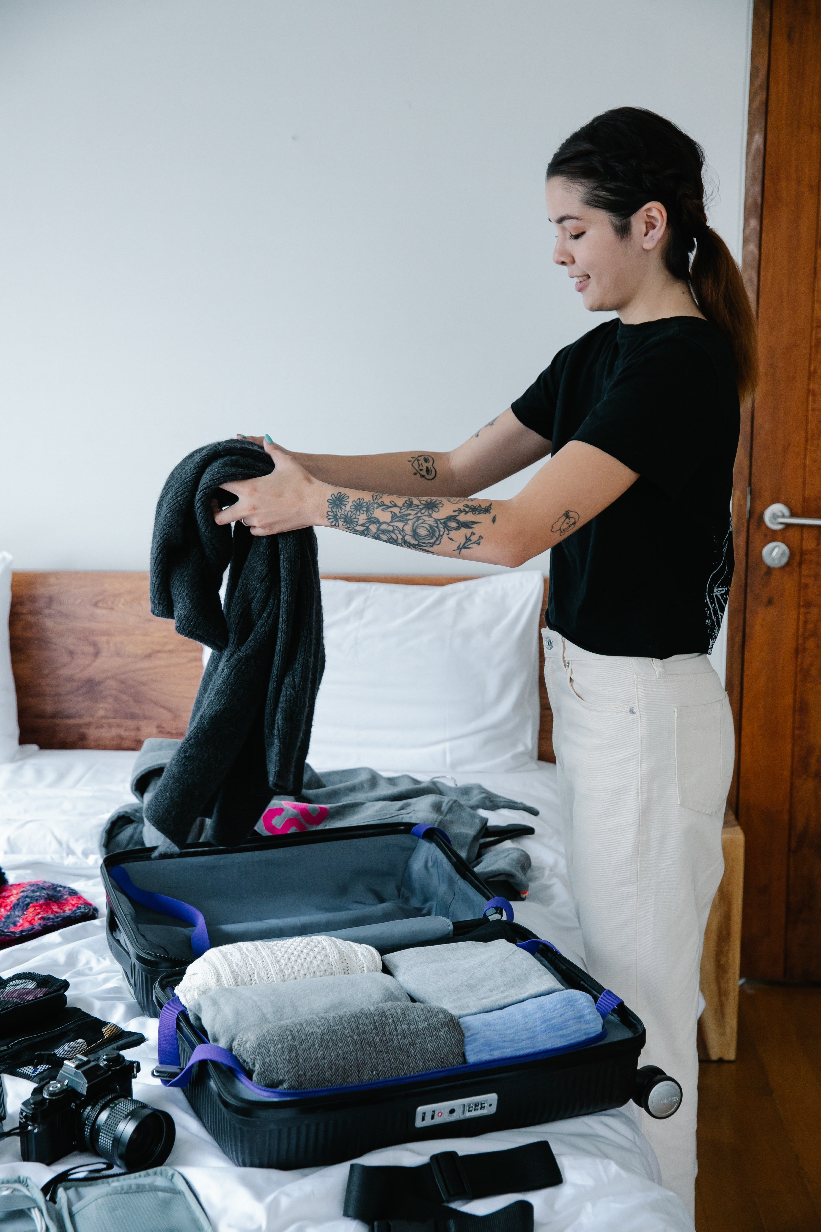 Mujer acomodando ropa en un maletín. | Foto: Pexels