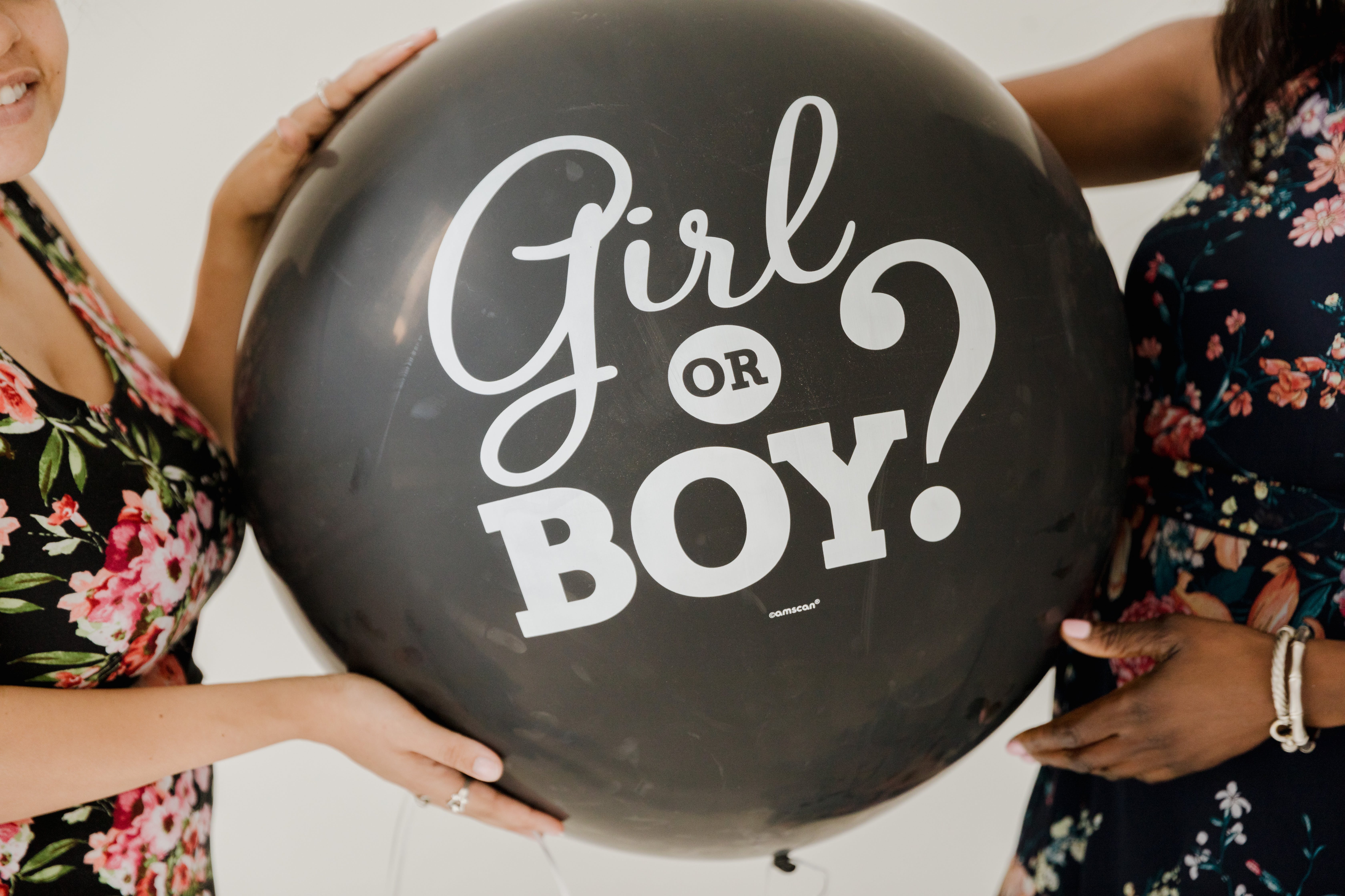 Two women holding a gender reveal balloon | Source: Pexels