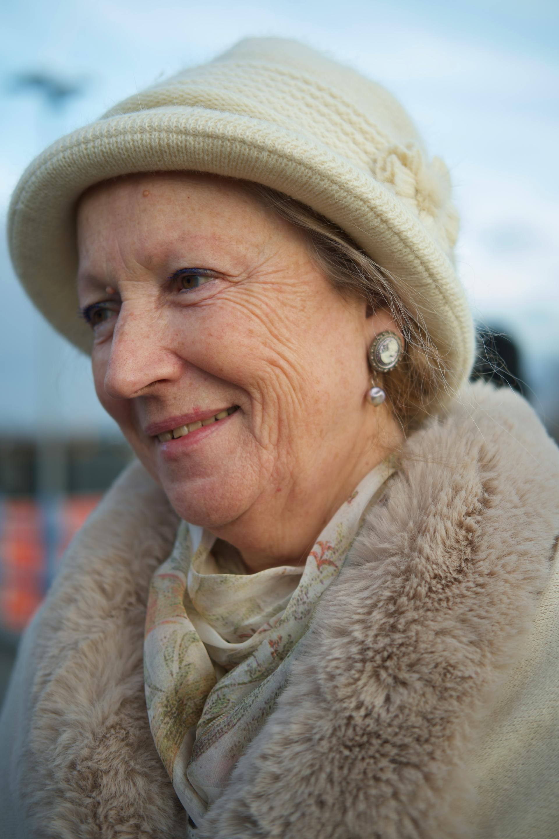 Smiling older woman in white fur coat and knitted hat | Source: Pexels