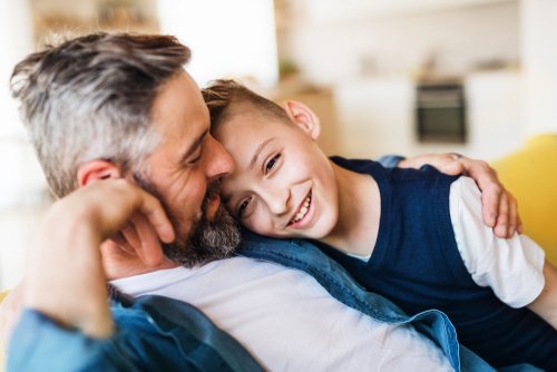 Padre maduro con pequeño hijo sentado en el sofá en el interior, descansando. | Fuente: Shutterstock Padre maduro con pequeño hijo sentado en el sofá en el interior, descansando. | Fuente: Shutterstock