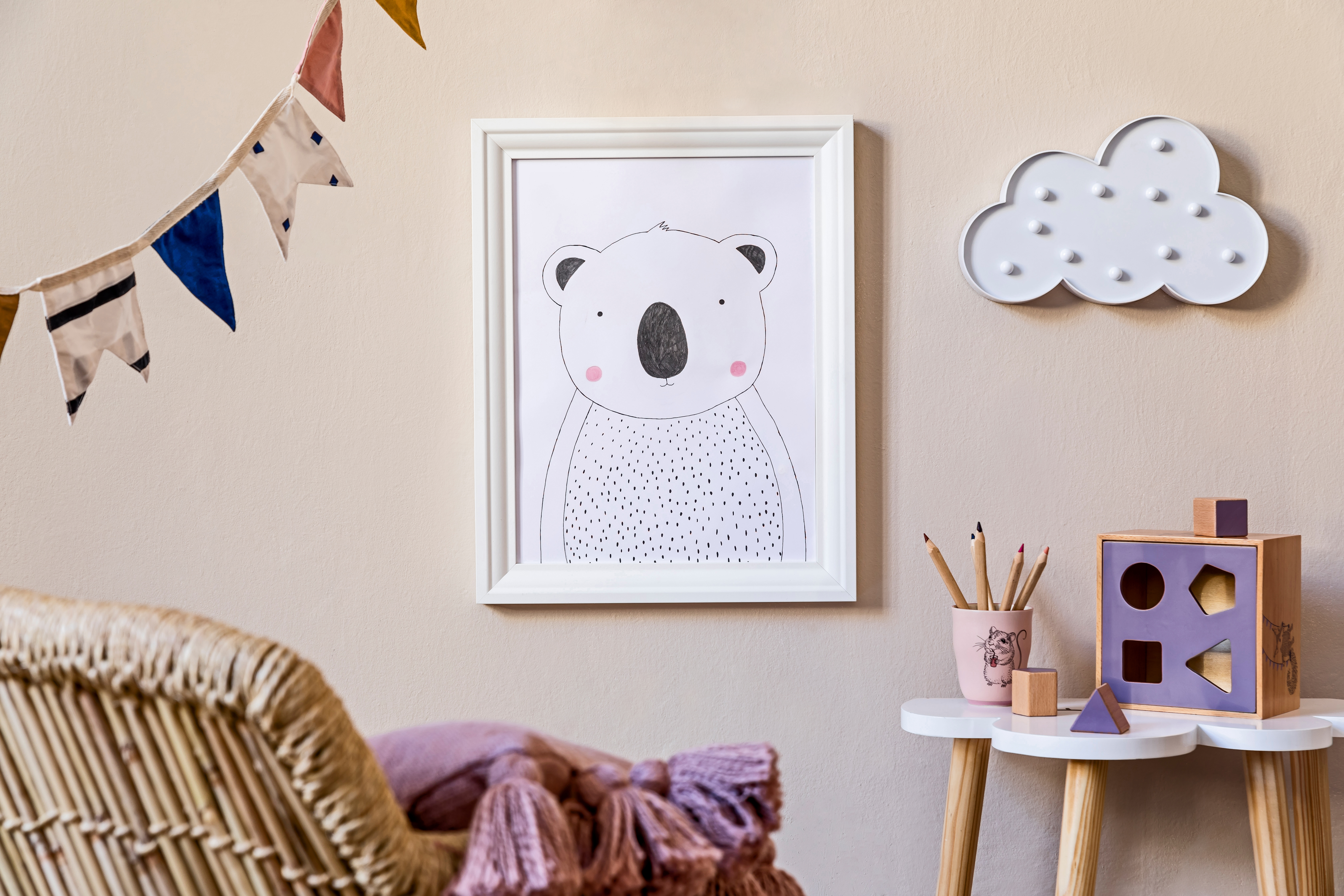 Stylish scandinavian nursery interior with mock up photo frame, wooden toys, design furniture, pillows and accessories. Beautiful decoration on the beige background wall. Home decor for children room | Source: Getty Images