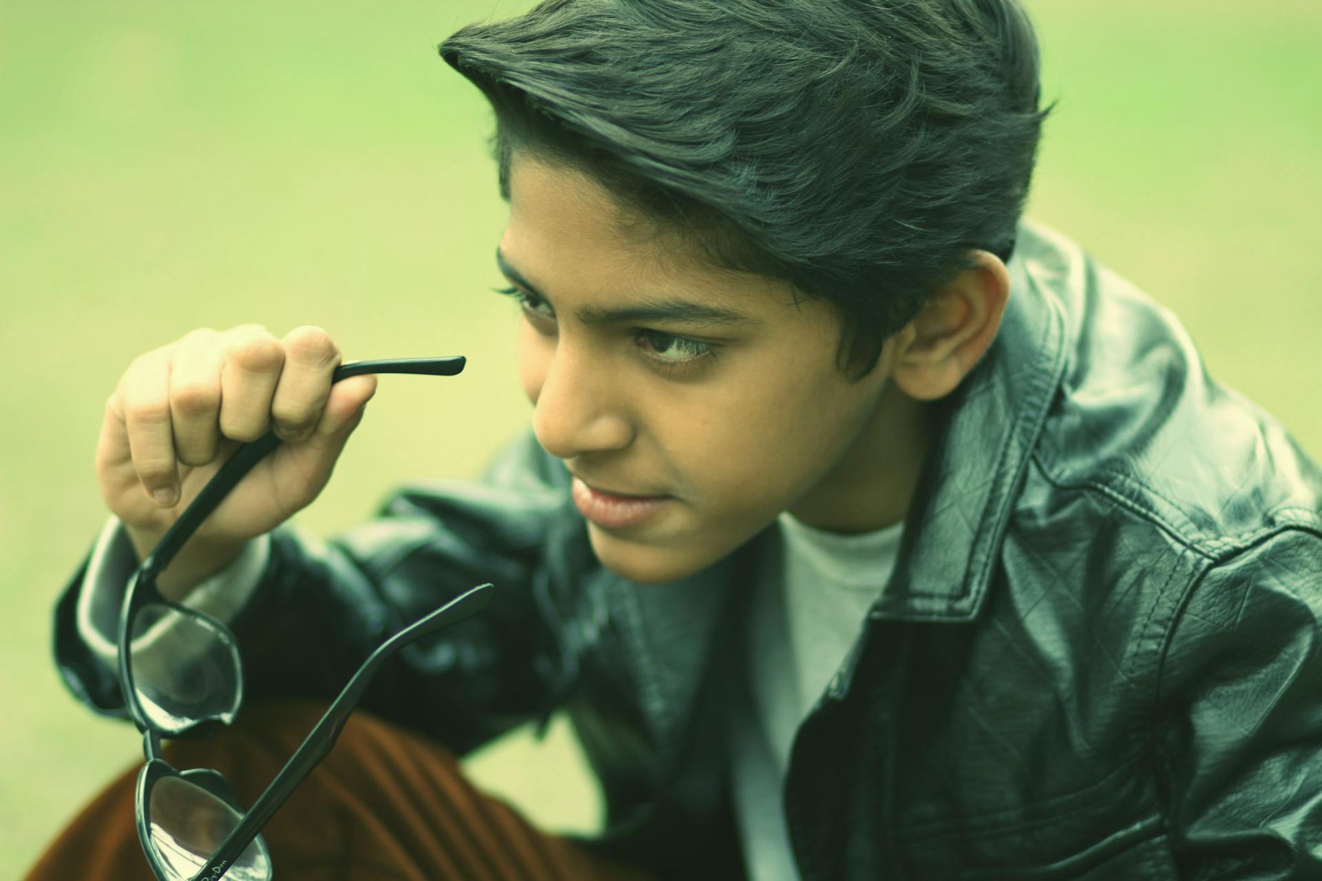 A teen boy removing his glasses | Source: Pexels