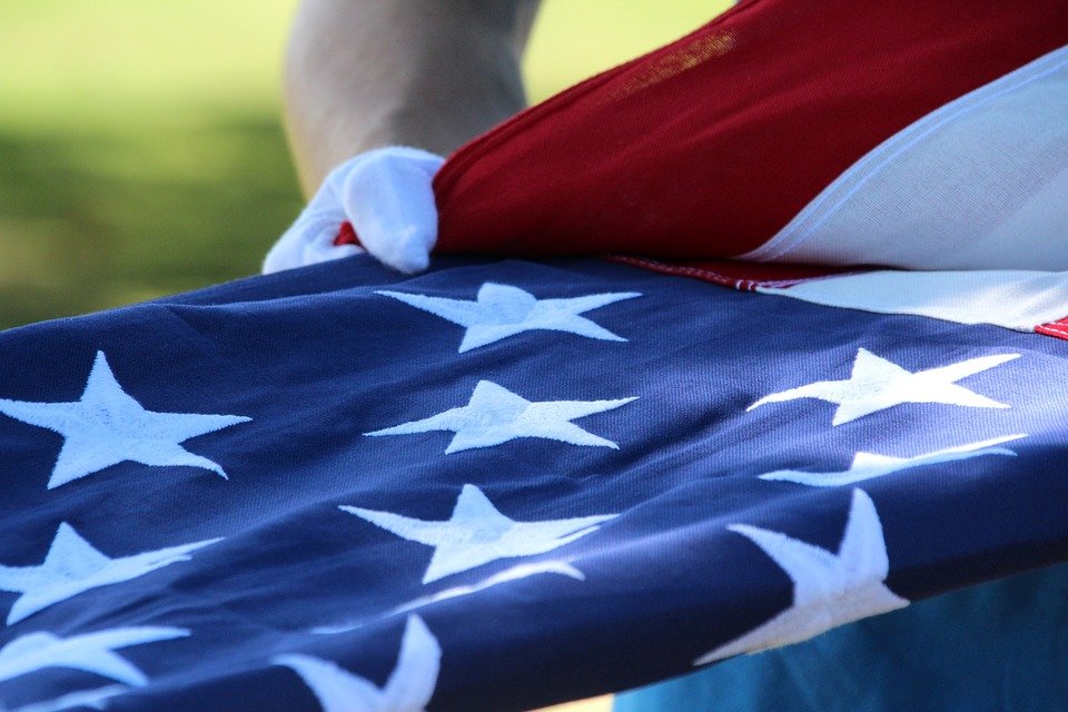 Soldiers with the flag at a  veterans memorial |  Photo: Pexels